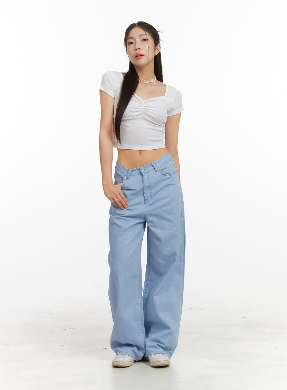 Solid Cotton Loose Fit Straight Jeans OA429 in light blue, full-length front view on model, relaxed wide-fit straight leg, low rise, styled with white ruched crop top and white sneakers.