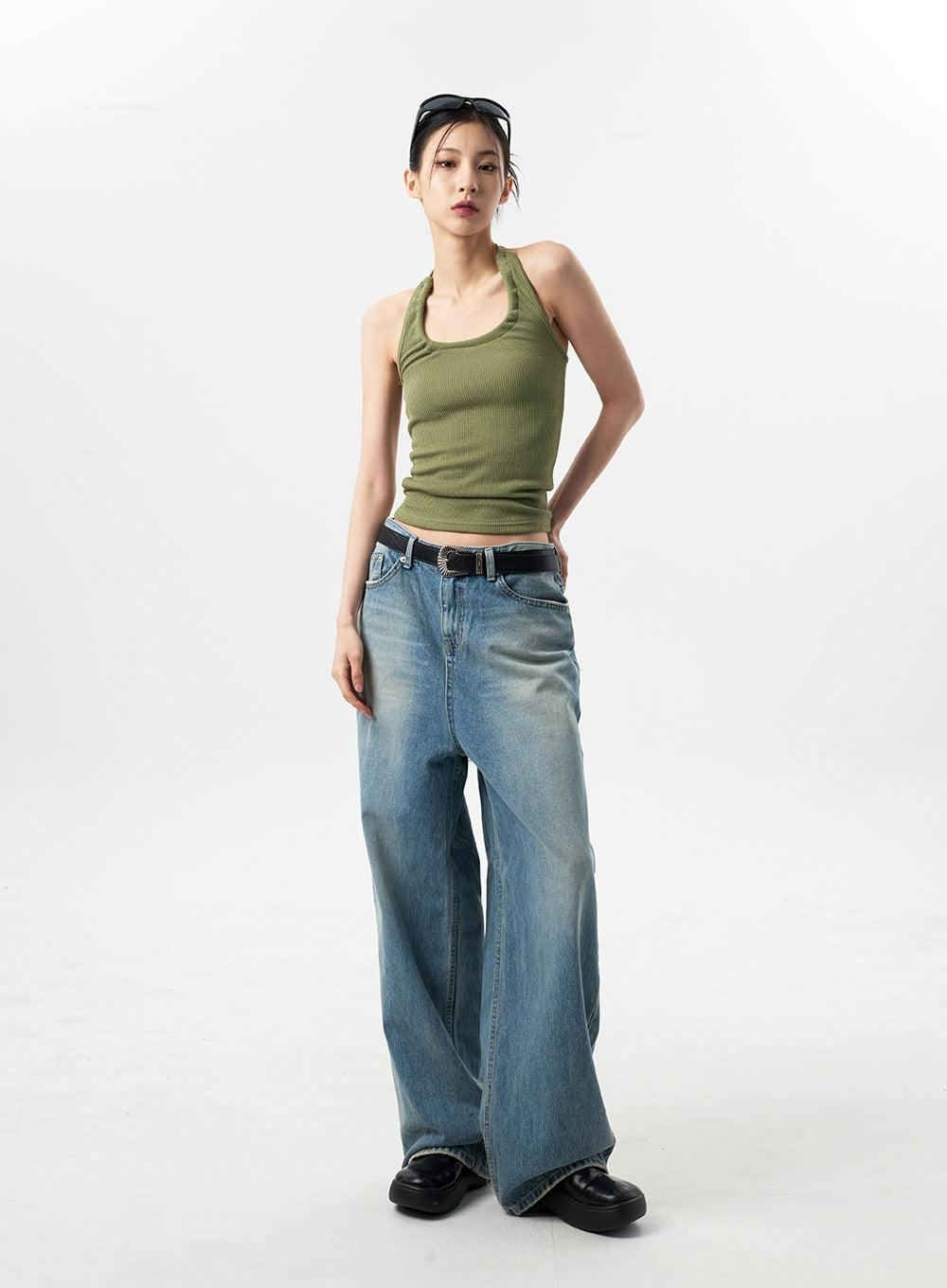 Oversized Jeans Unisex CY312 in washed blue, full-length front view on model facing camera, relaxed wide-leg denim, styled with green halter crop top and black belt.
