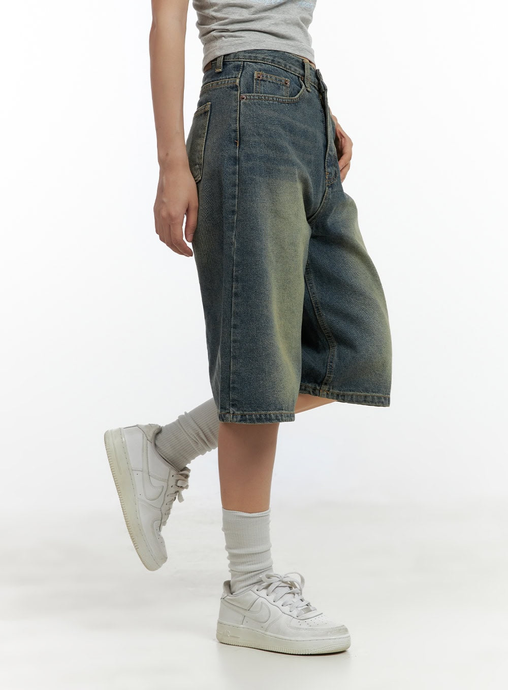 Slim Fit Bermuda Jorts CL410 in blue, side view on model with leg raised, wide-leg washed denim showing midi length and stitched hem, worn with white sneakers.