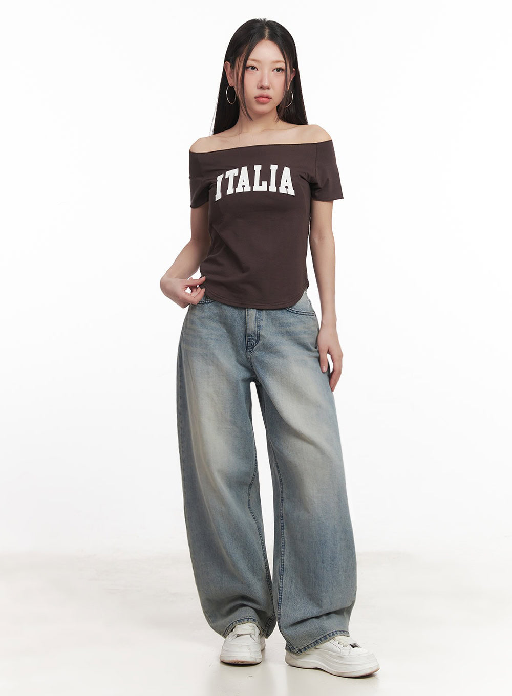 Casey Washed Baggy Jeans IM528 in light blue, full-length front shot on model standing straight, ultra-wide baggy silhouette with faded wash, styled with brown graphic crop top and white sneakers.
