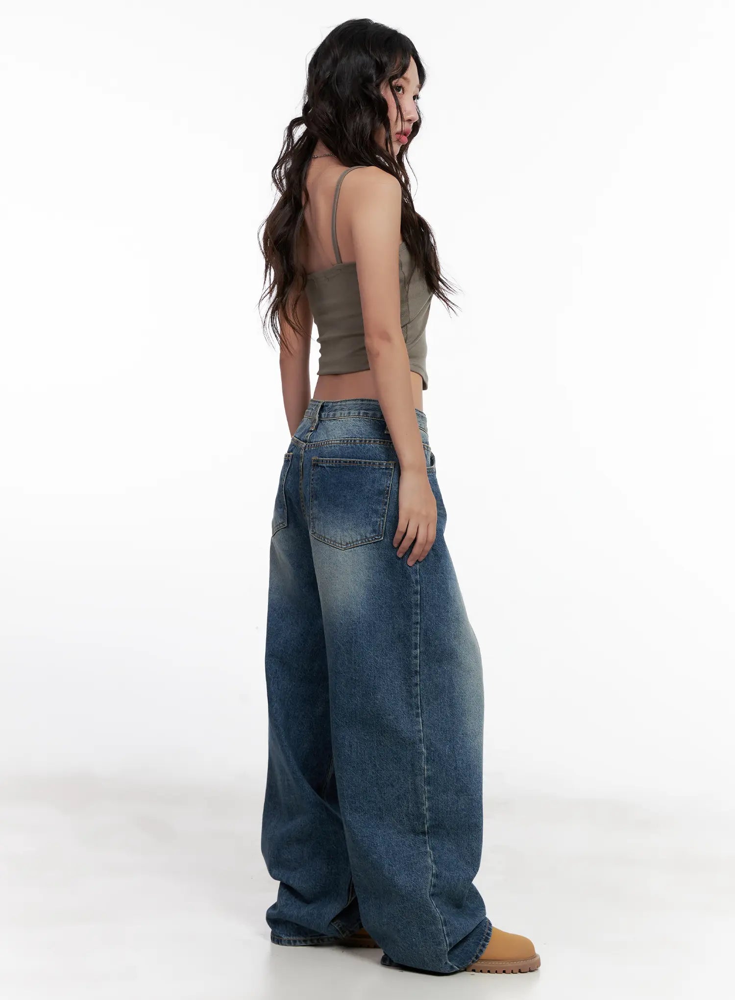 Miji Wide-Leg Washed Denim Jeans CL521 in dark blue, side-rear angle on model looking back, balloon wide leg silhouette, back pocket visible, paired with khaki crop cami and tan boots.