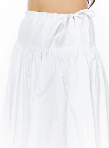 Basic Ribbon Maxi Skirt CU522 in white, close-up detail of side ribbon tie and gathered elastic waistband, crisp cotton fabric with tiered gathering visible at hip.