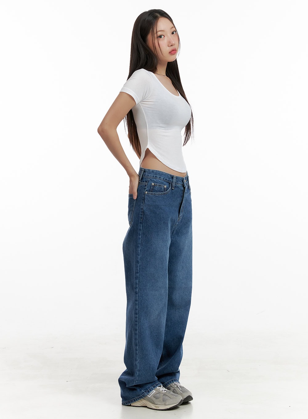 Eva Blue Washed Baggy Jeans CL431 in blue, side full-length view on model, wide-fit washed denim showing roomy leg silhouette, paired with white crop tee and grey sneakers.