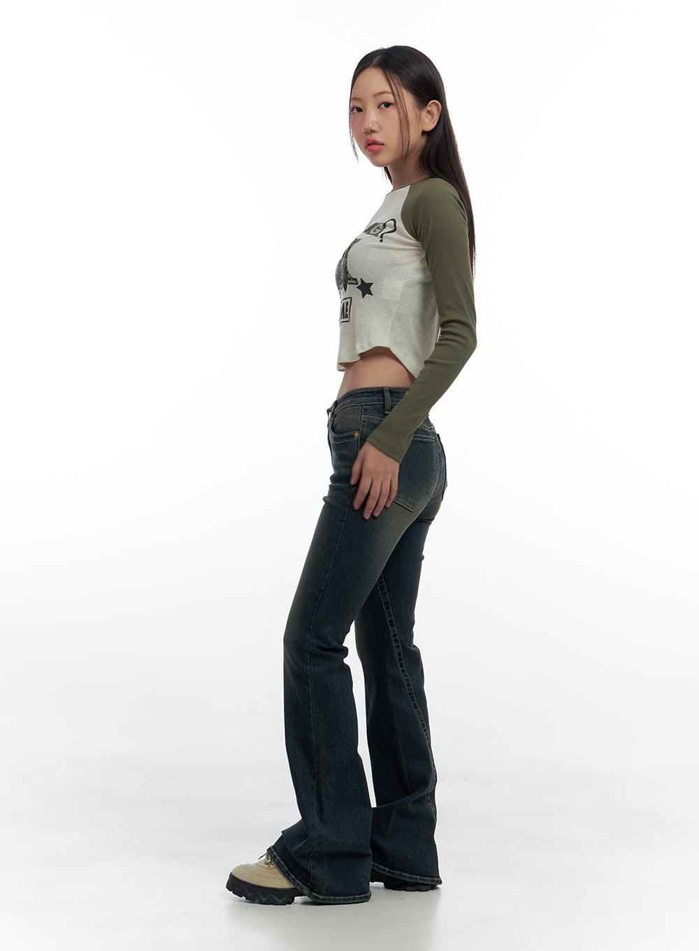 Aspen SlimFit Washed Bootcut Denim Jeans CS424 in dark blue, side profile shot on model, slim through thigh flaring to bootcut hem, low-rise waist, paired with green raglan crop top and boots.