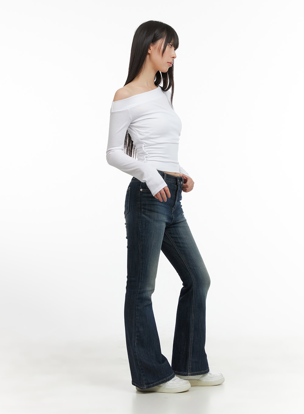 Remy Washed Bootcut Jeans CG420 in blue, side profile shot on model, slim fit washed denim showing bootcut flare from knee, paired with white off-shoulder top and white sneakers.