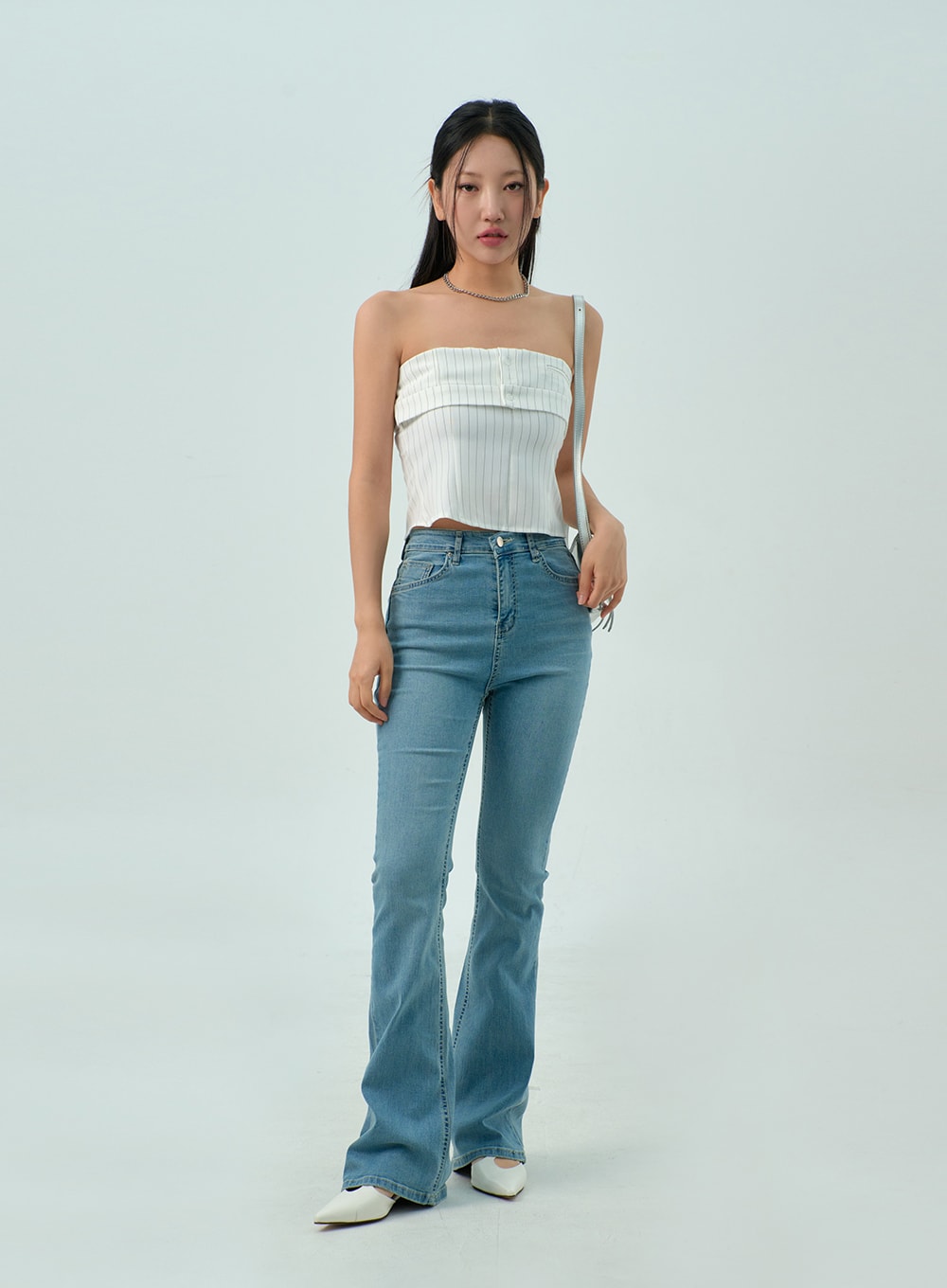 Light Wash Bootcut Jeans CY330 in light blue, full front view on model with crossbody bag, slim-fit washed denim, bootcut silhouette elongating the legs, styled with white crop top.