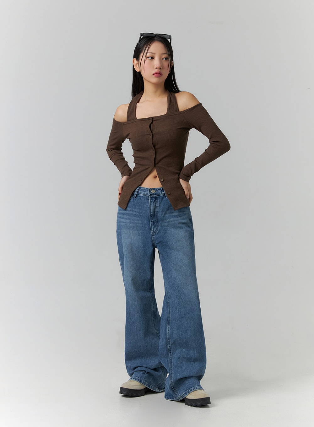 Wide Leg Jeans J12 in blue, full-body slight side angle on model with hands on hips, wide-leg cotton denim with gradation wash, street-style look with brown off-shoulder top and chunky sneakers.