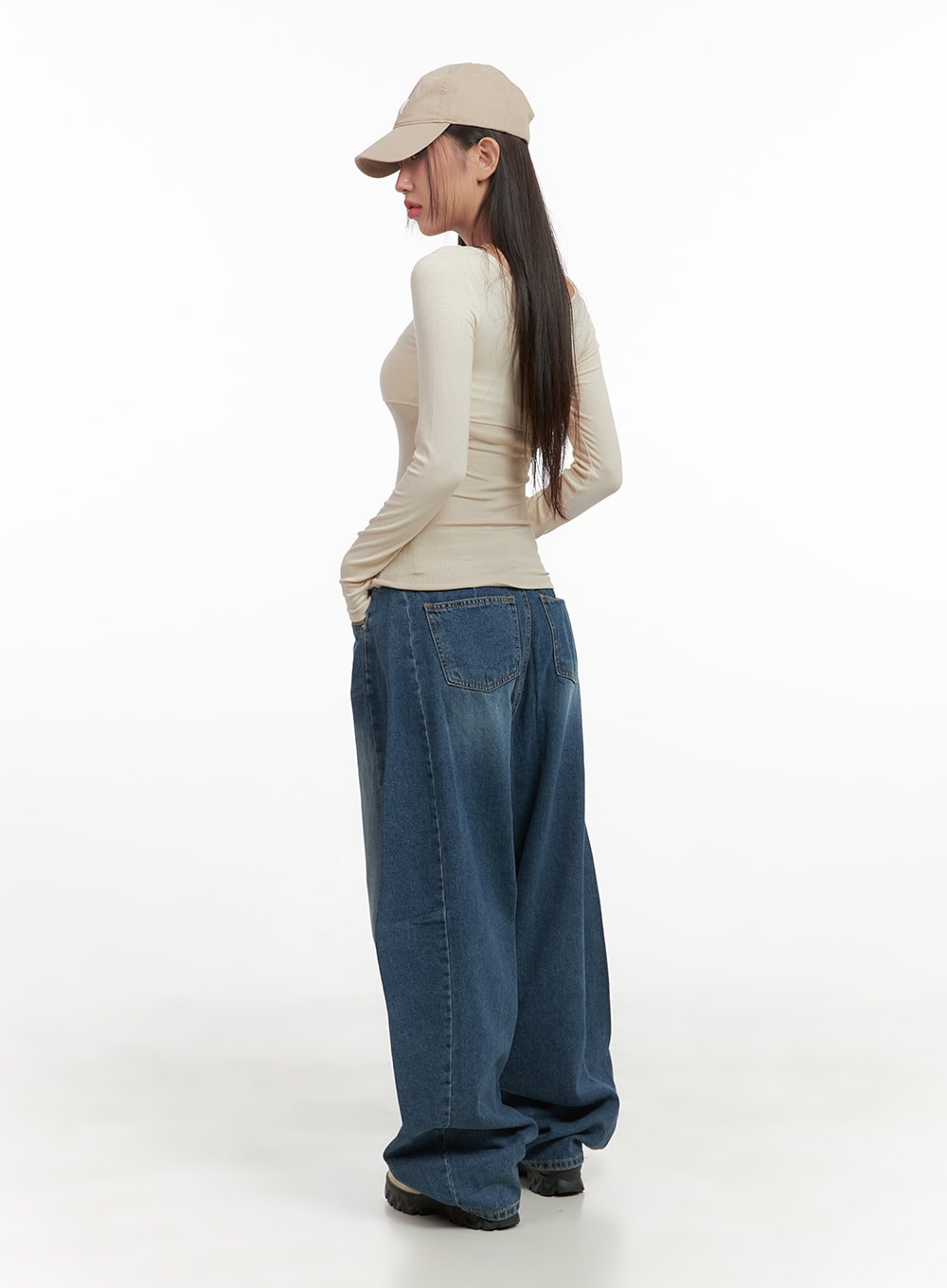 Lacey Washed Denim Baggy Jeans CO404 in blue, back three-quarter view on model, showing dual back pockets and wide washed denim silhouette, paired with beige top and cap.