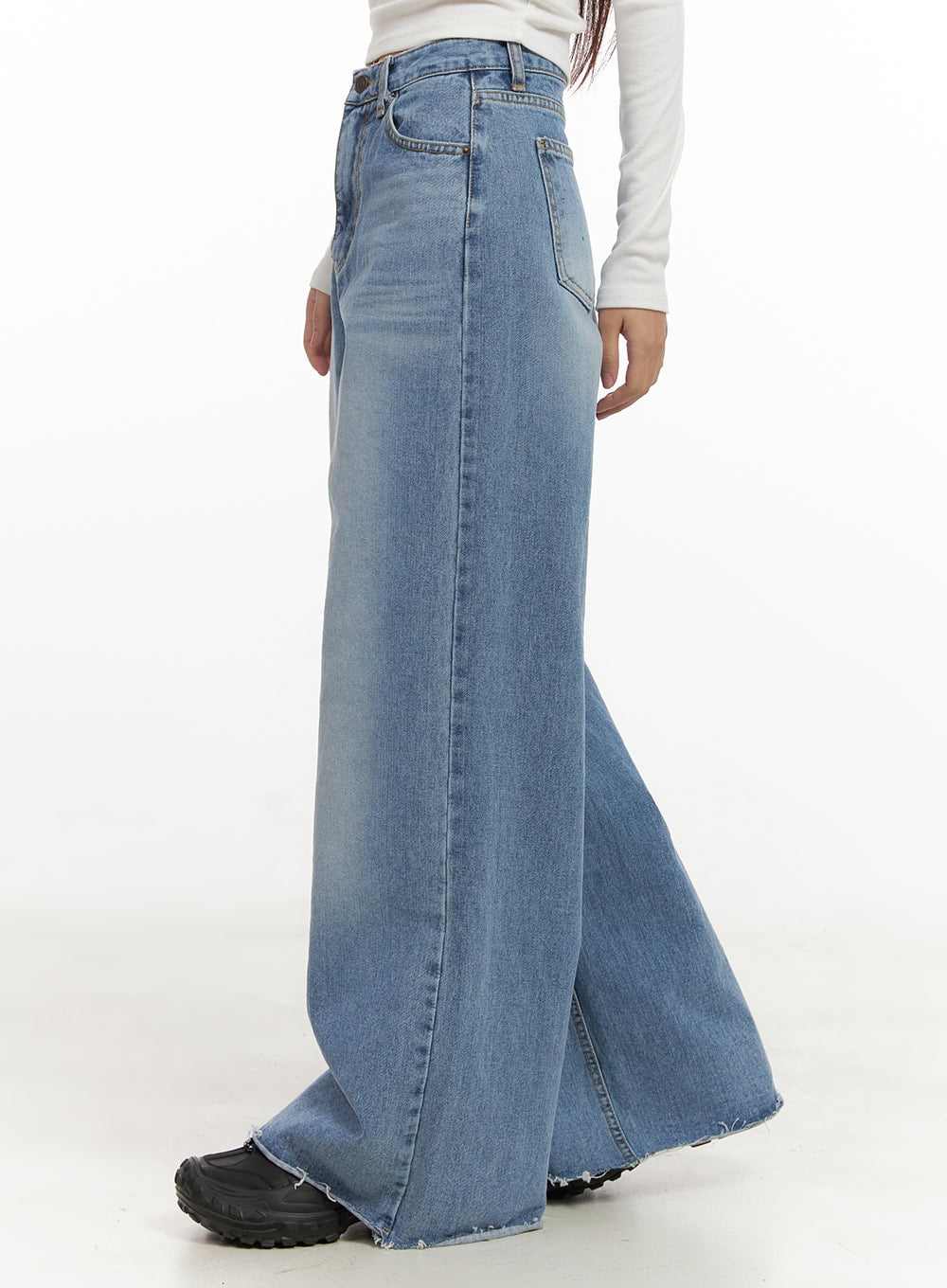 Melody Chic Flare Wide Leg Jeans CN428 in light blue, side view on model, showing exaggerated flare leg and raw destroyed hem, high-rise waist, paired with white long-sleeve top and black sneakers.