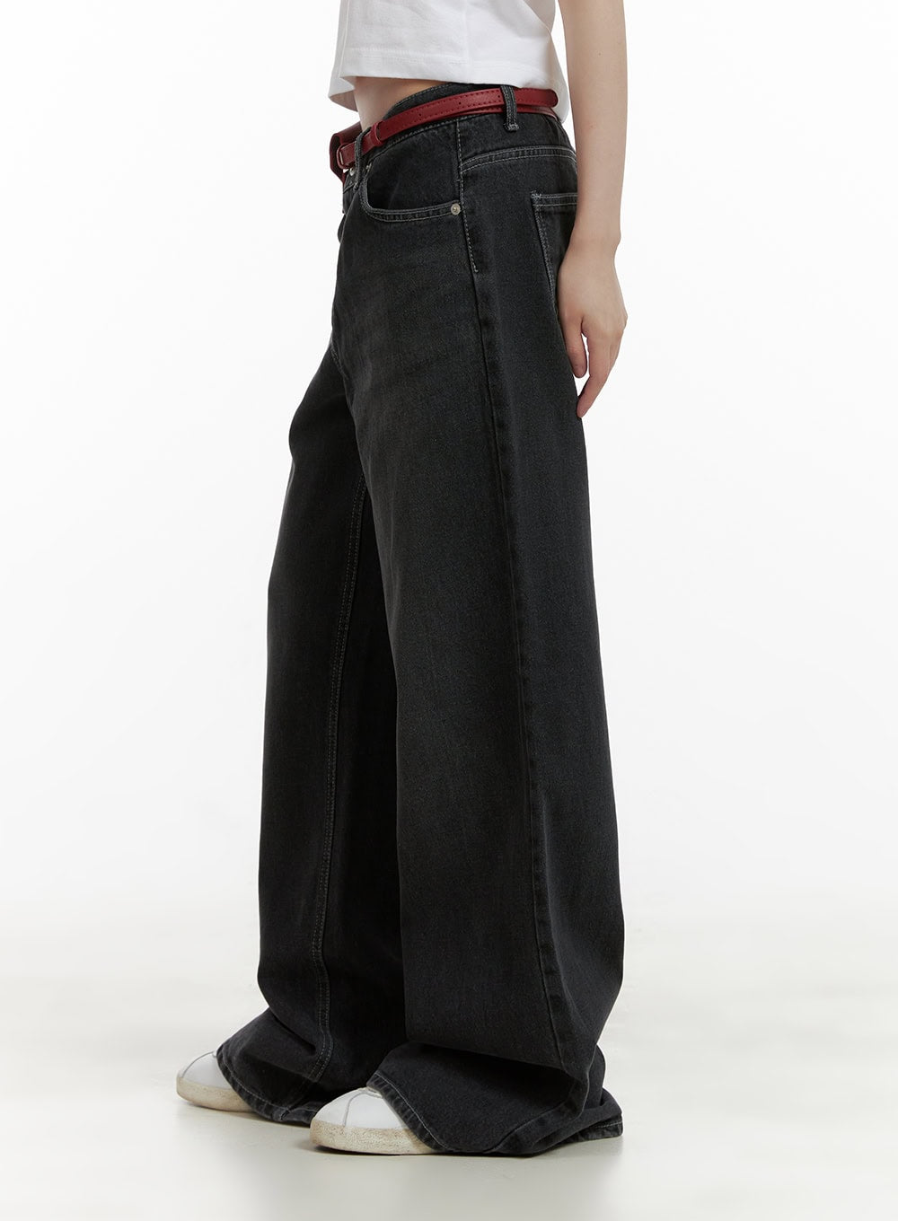 Low Rise Baggy Jeans CU410 in black, side half-body shot on model, wide-fit washed cotton denim showing low waist and roomy leg, with red belt.