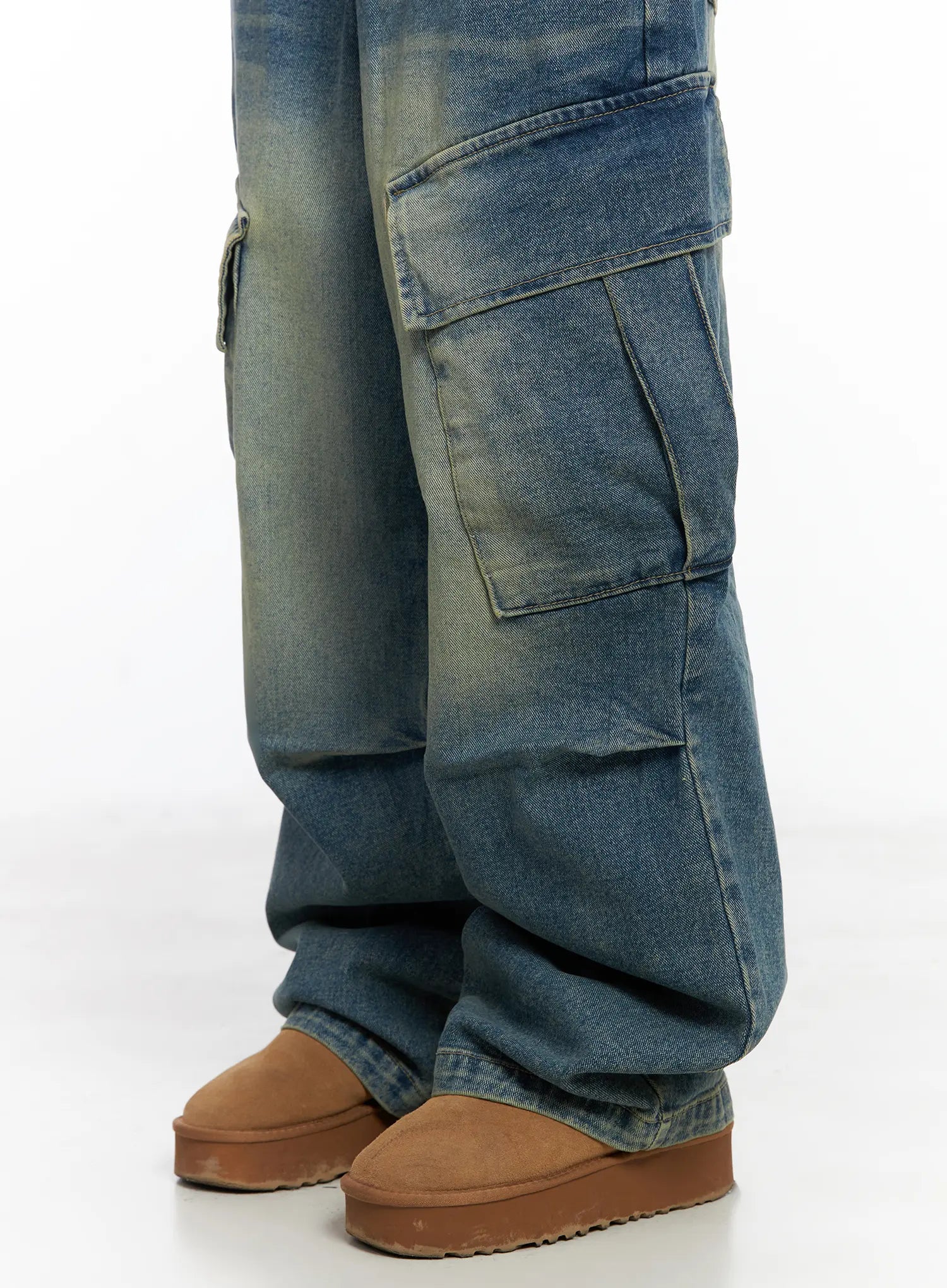 Jake Wide-Leg Cargo Jeans CJ515 in blue, lower-leg close-up on model, highlighting large flap cargo pocket, washed denim texture with yellow-tinted fading, and pooling hem over tan boots.