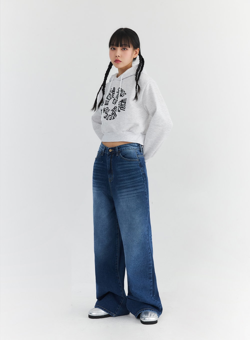 Washed Blue Wide Jeans CN301 in blue, three-quarter side angle on model, showing wide-leg drape and washed fade detail, styled with a grey crop hoodie and silver metallic footwear.