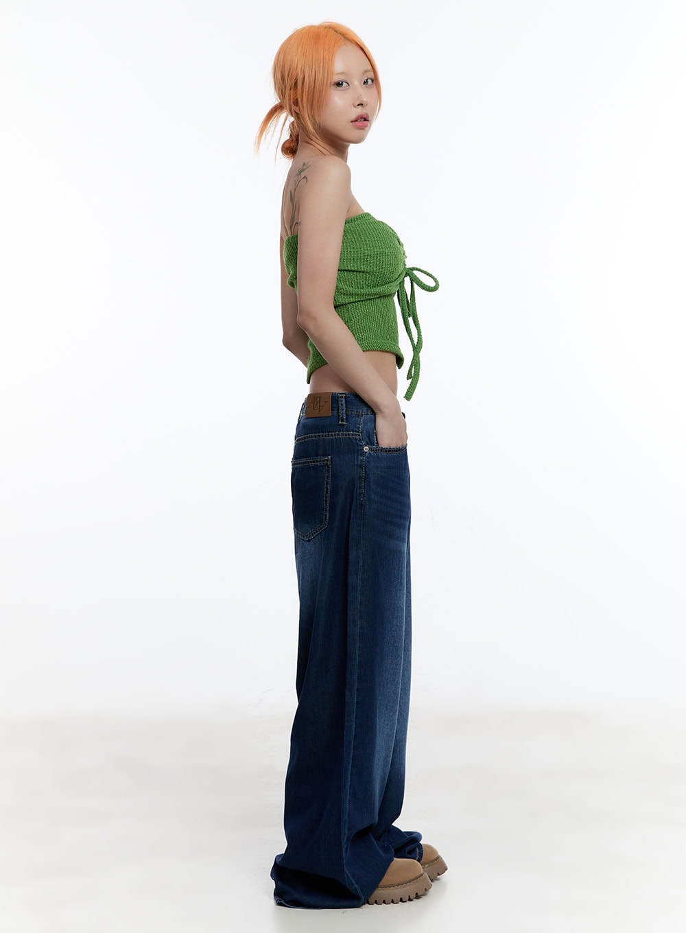 Jill Baggy Jeans CY530 in dark blue, side view on model, showing low-rise waistband with leather patch, wide-leg drape, and floor-grazing length with green bandeau top.