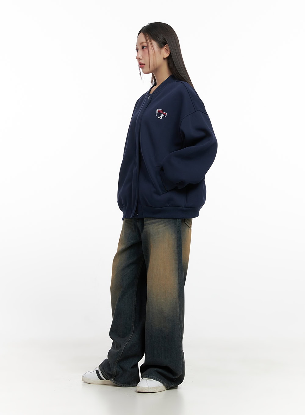 Bryana Cotton Comfort Wide Leg Jeans CN419 in dark blue, side view on model, amber-toned washed denim wide leg silhouette, paired with navy bomber jacket and white sneakers, showing leg drape.