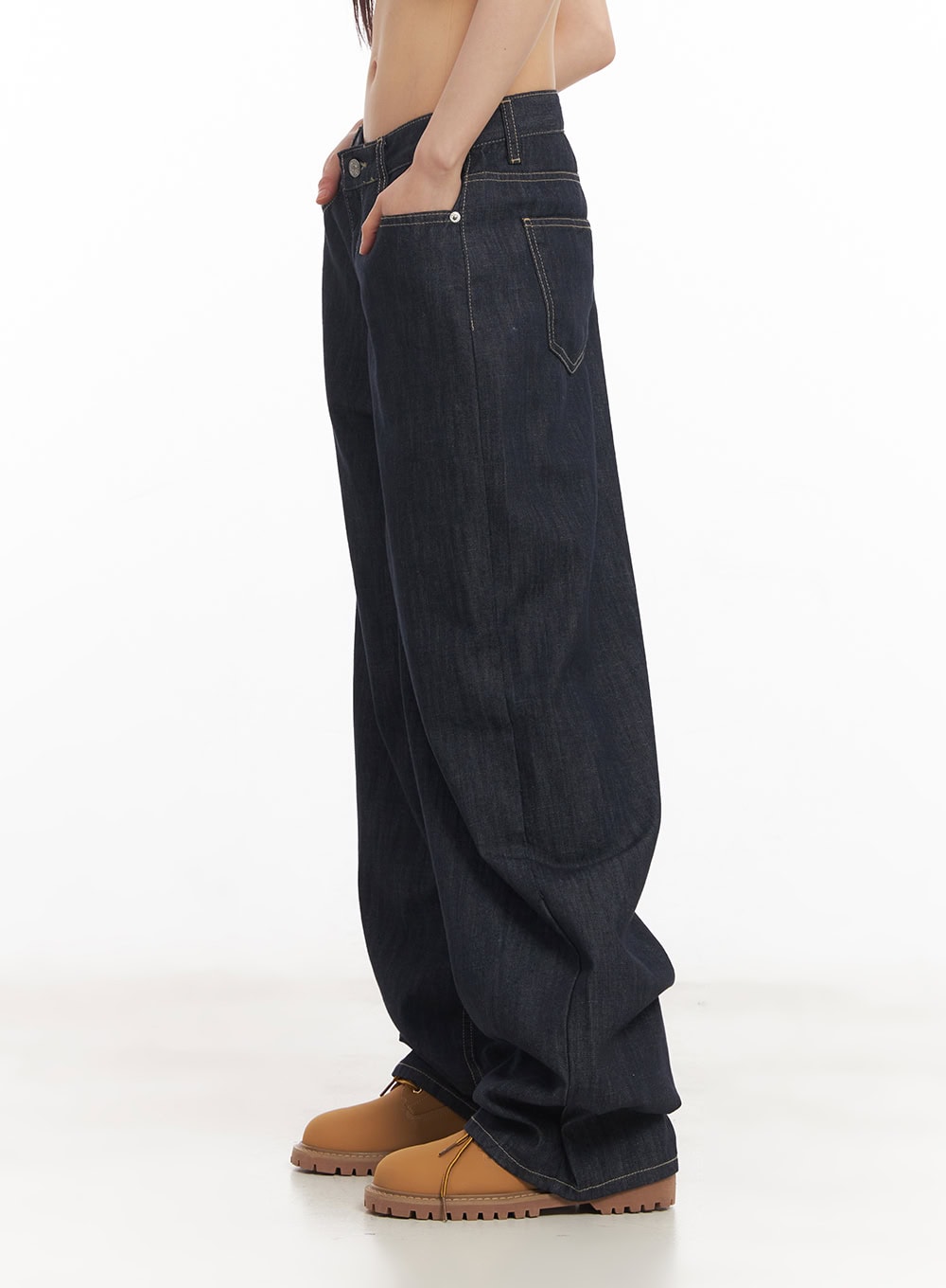 Ivara Wide-Leg Jeans CA522 in dark blue, side view on model with hand in back pocket, showing relaxed wide-leg silhouette, contrast stitching, and floor-grazing hem on tan boots.
