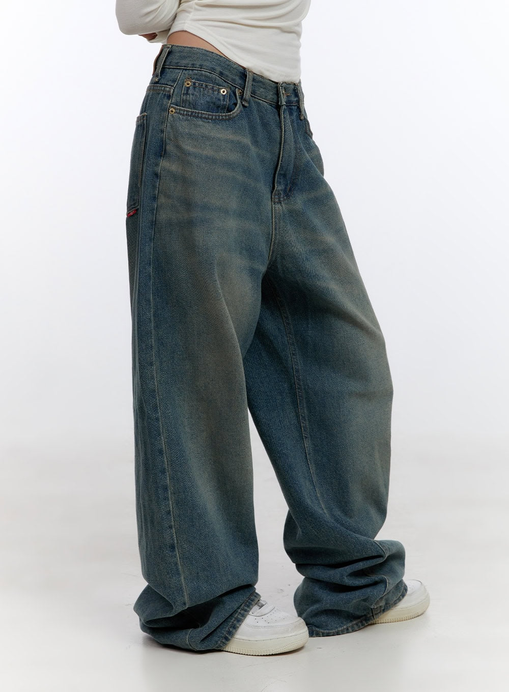 Zola Casual Fit Denim Jeans CO422 in blue, side angle close-up on model, wide-leg silhouette with vintage washed cotton denim, side pocket detail, stacked hem over white sneakers.