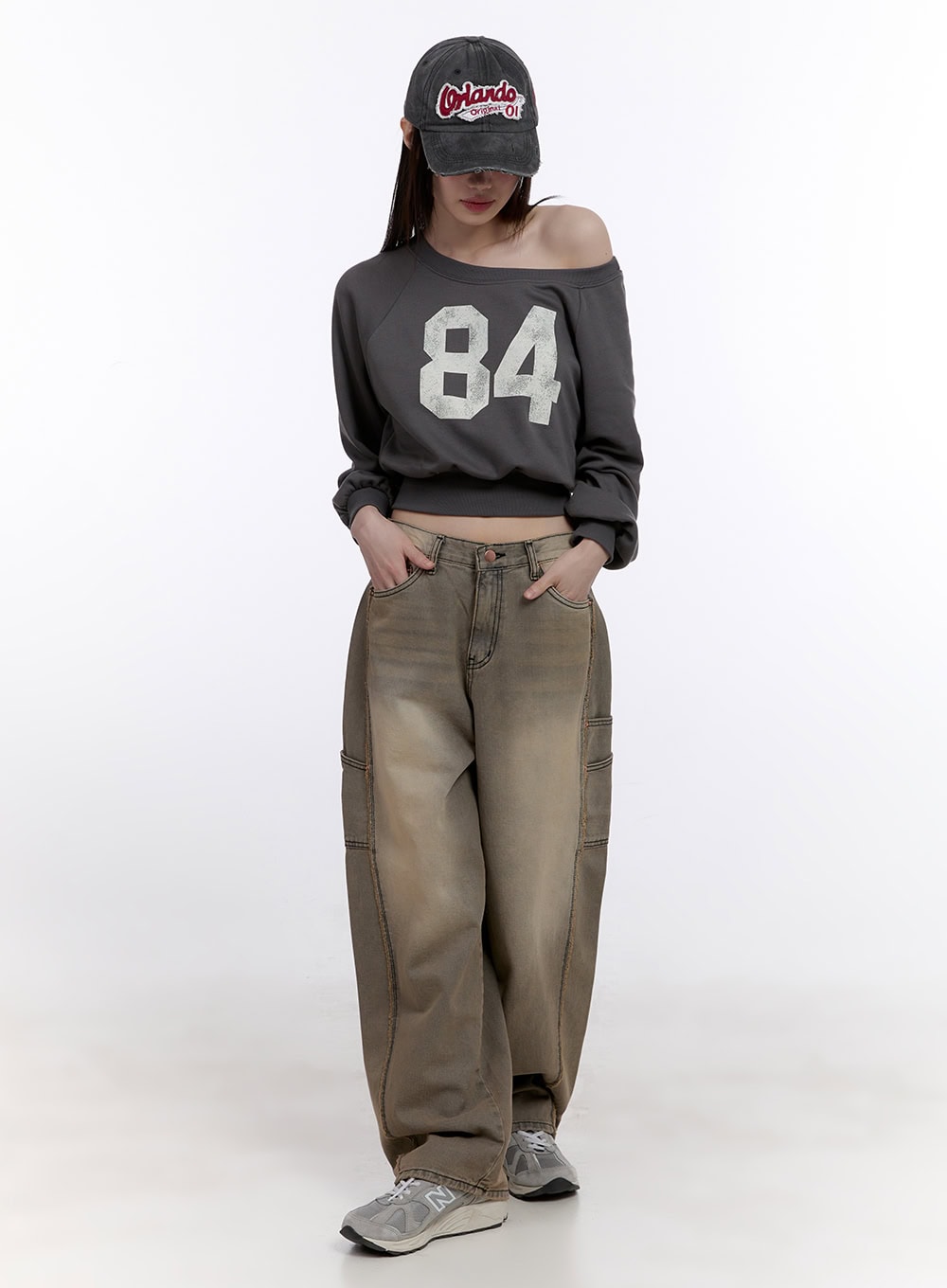 Sara Stitched Pocket Baggy Jeans CF512 in Beige, full-length front shot on model, baggy cotton denim with washed finish, paired with off-shoulder crop sweatshirt and baseball cap.