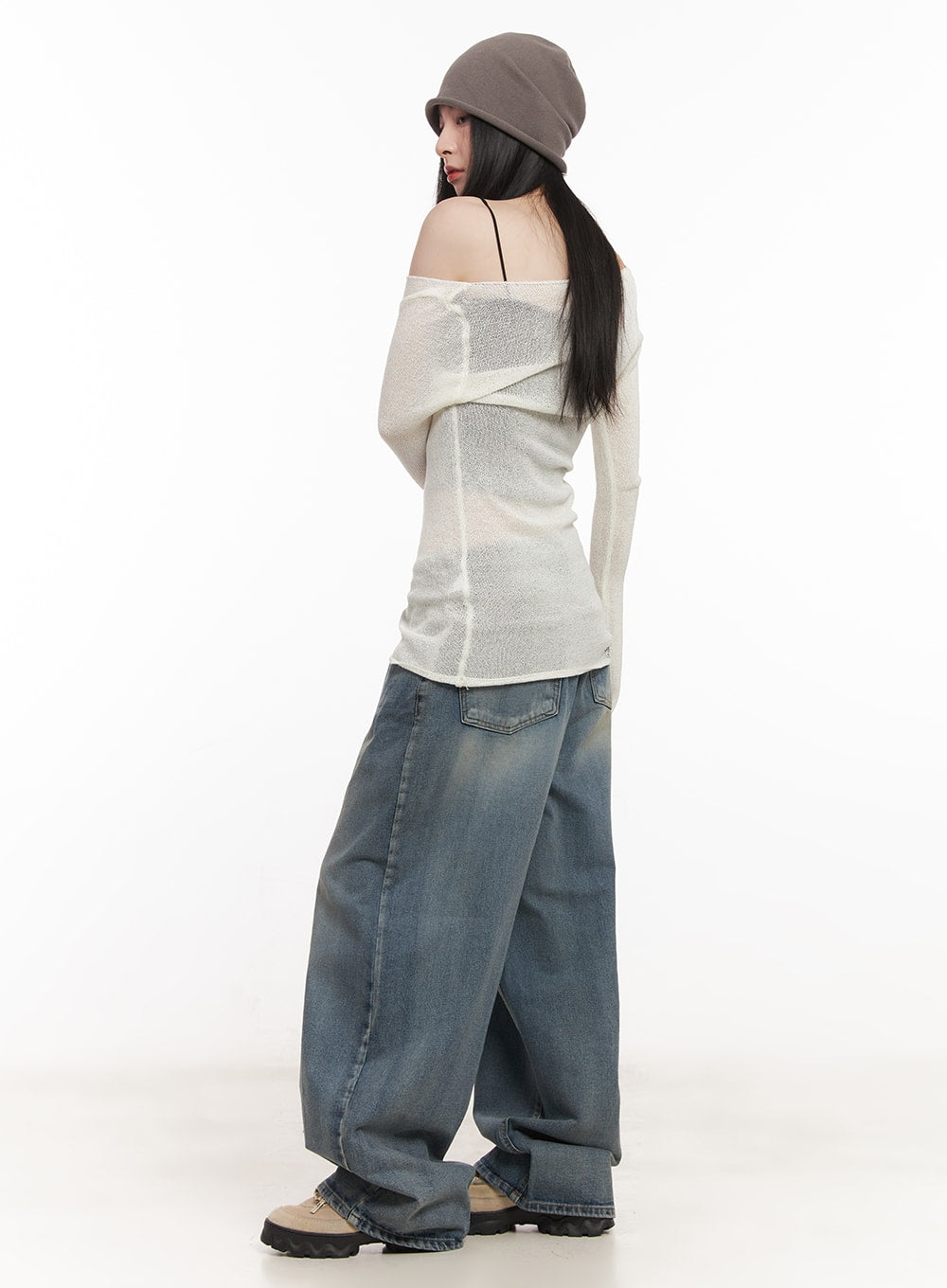 Shelly Washed Baggy Jeans CM518 in blue, back three-quarter view on model, oversized washed denim with voluminous wide leg and faded finish, paired with sheer knit top and beanie.