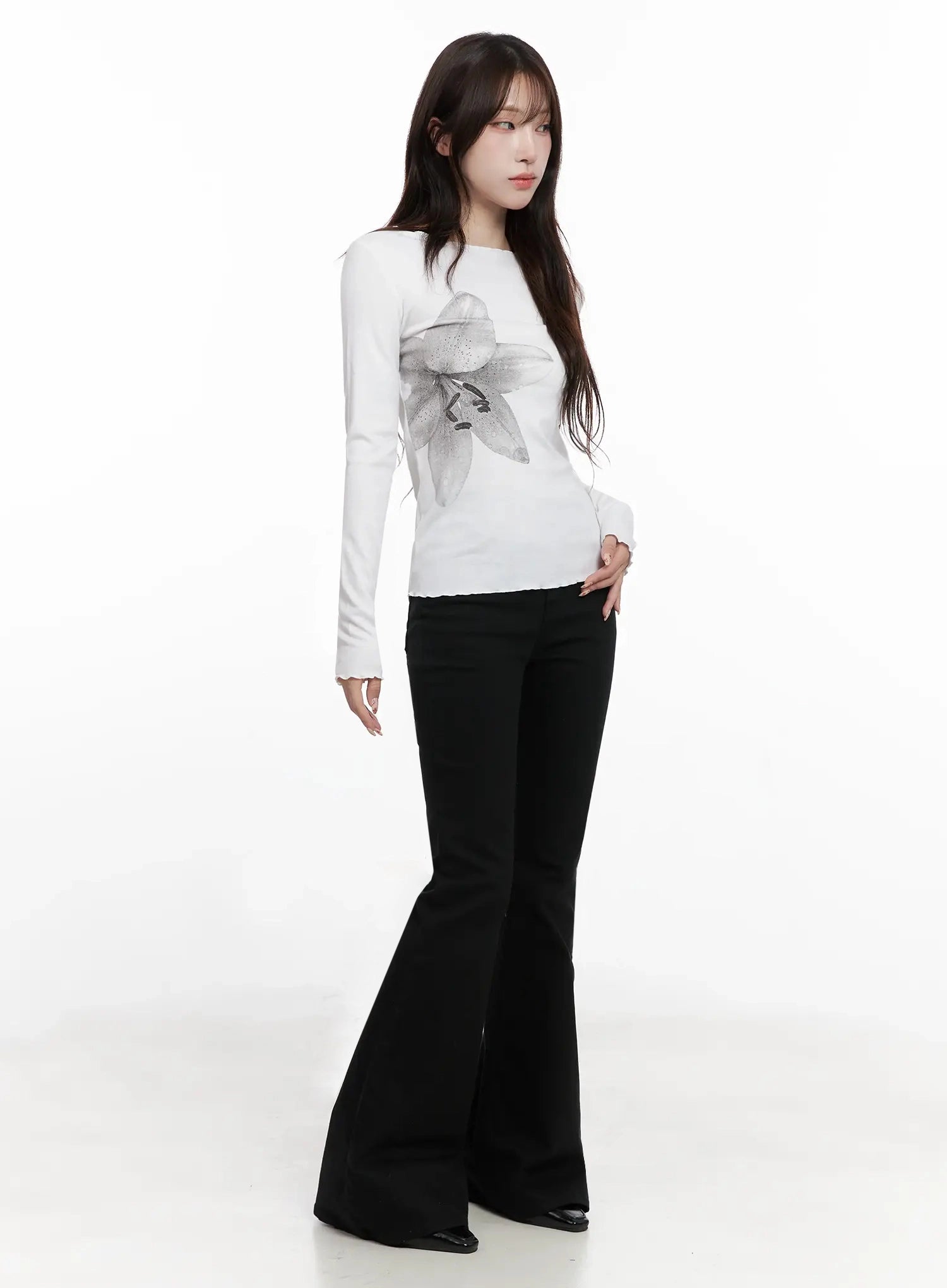 Dream Chic Black Flare Jeans IN514 in black, three-quarter side view on model, wide flare hem sweeping floor, paired with white printed long-sleeve tee, casual modern styling.