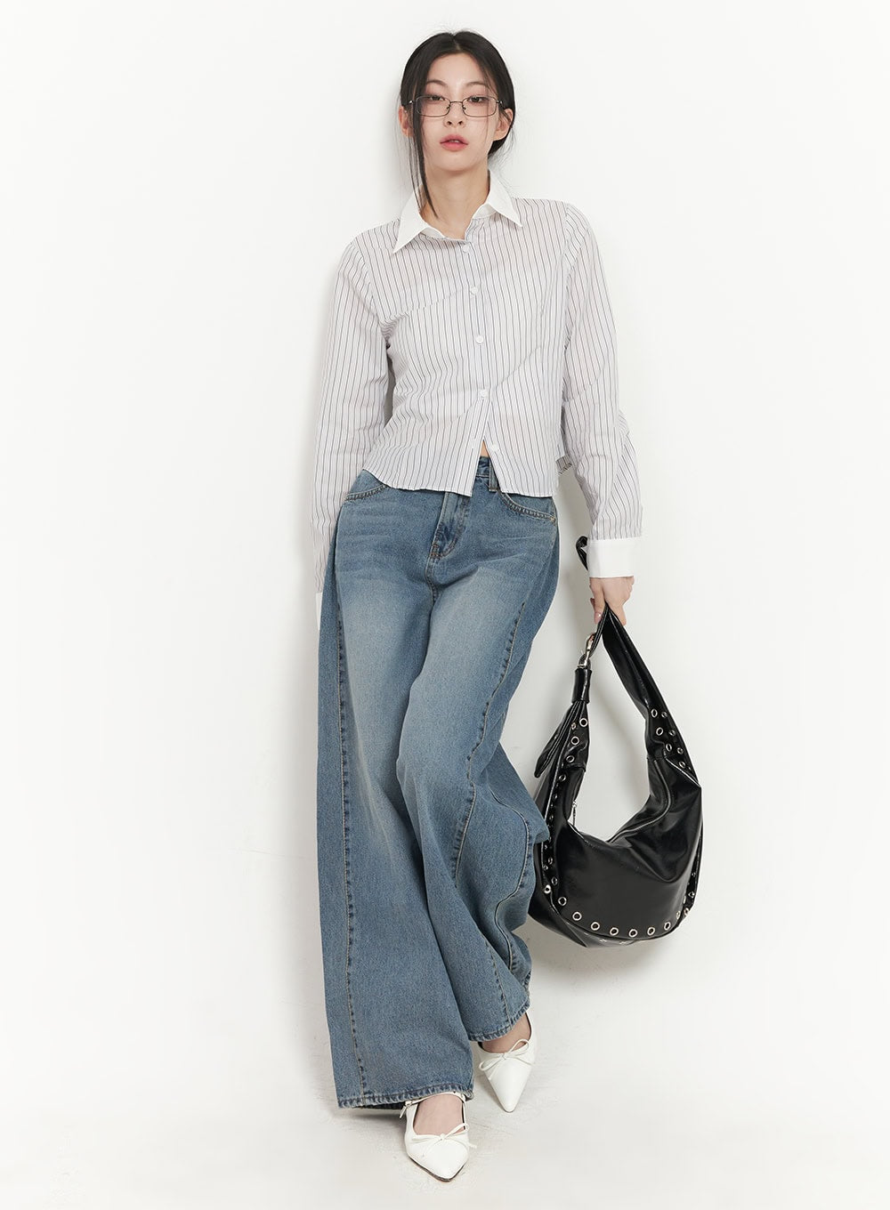 Andrea Wide-Leg Jeans CF514 in blue, full-length front styling shot, model leaning against wall, wide-leg washed denim, styled with striped shirt and black studded shoulder bag.