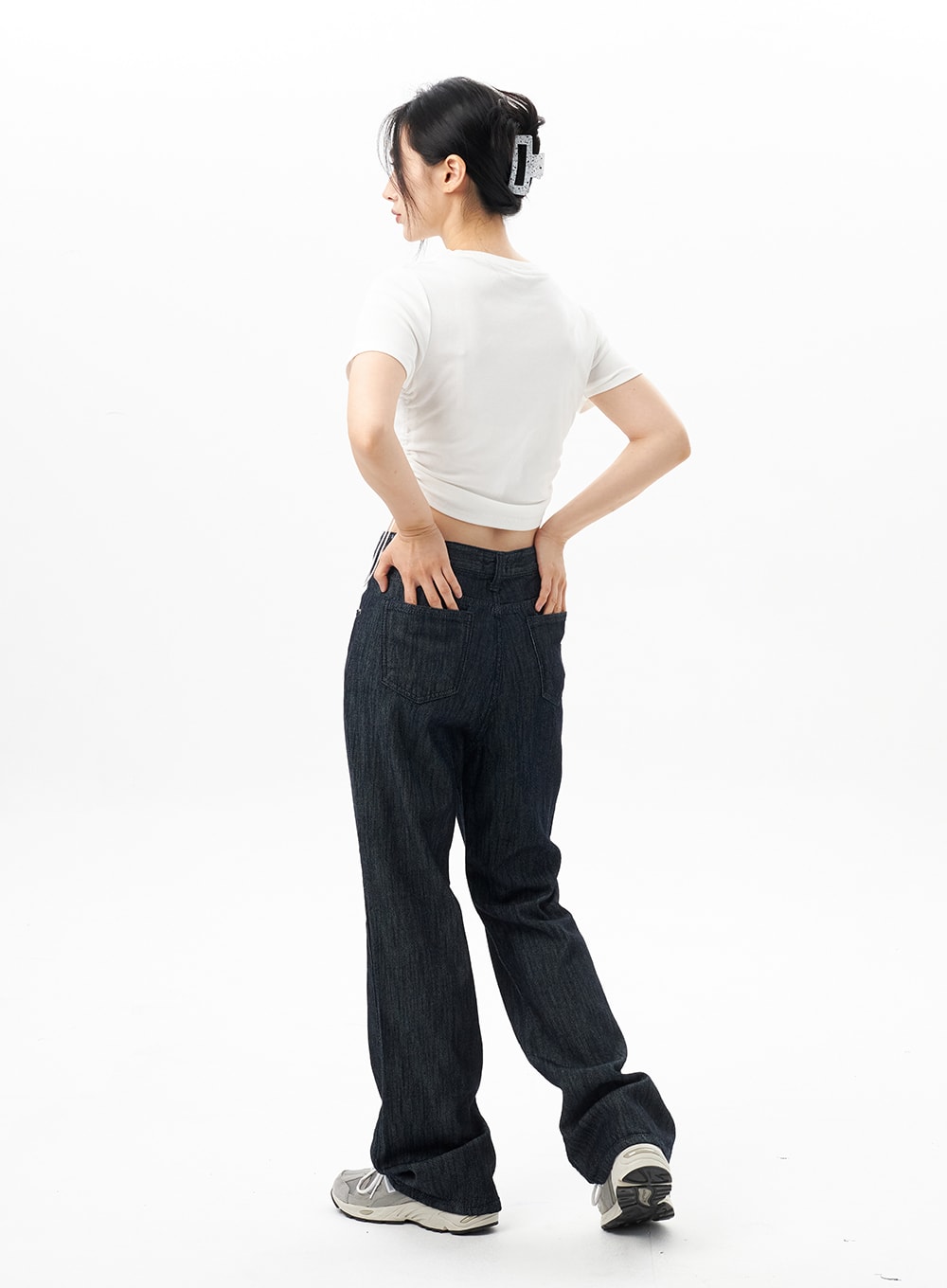 Dark Wash Mid-Rise Jeans OU314 in dark blue, back full-length view on model, bootcut flare hem pooling at sneakers, back patch pockets visible, paired with white crop tee.