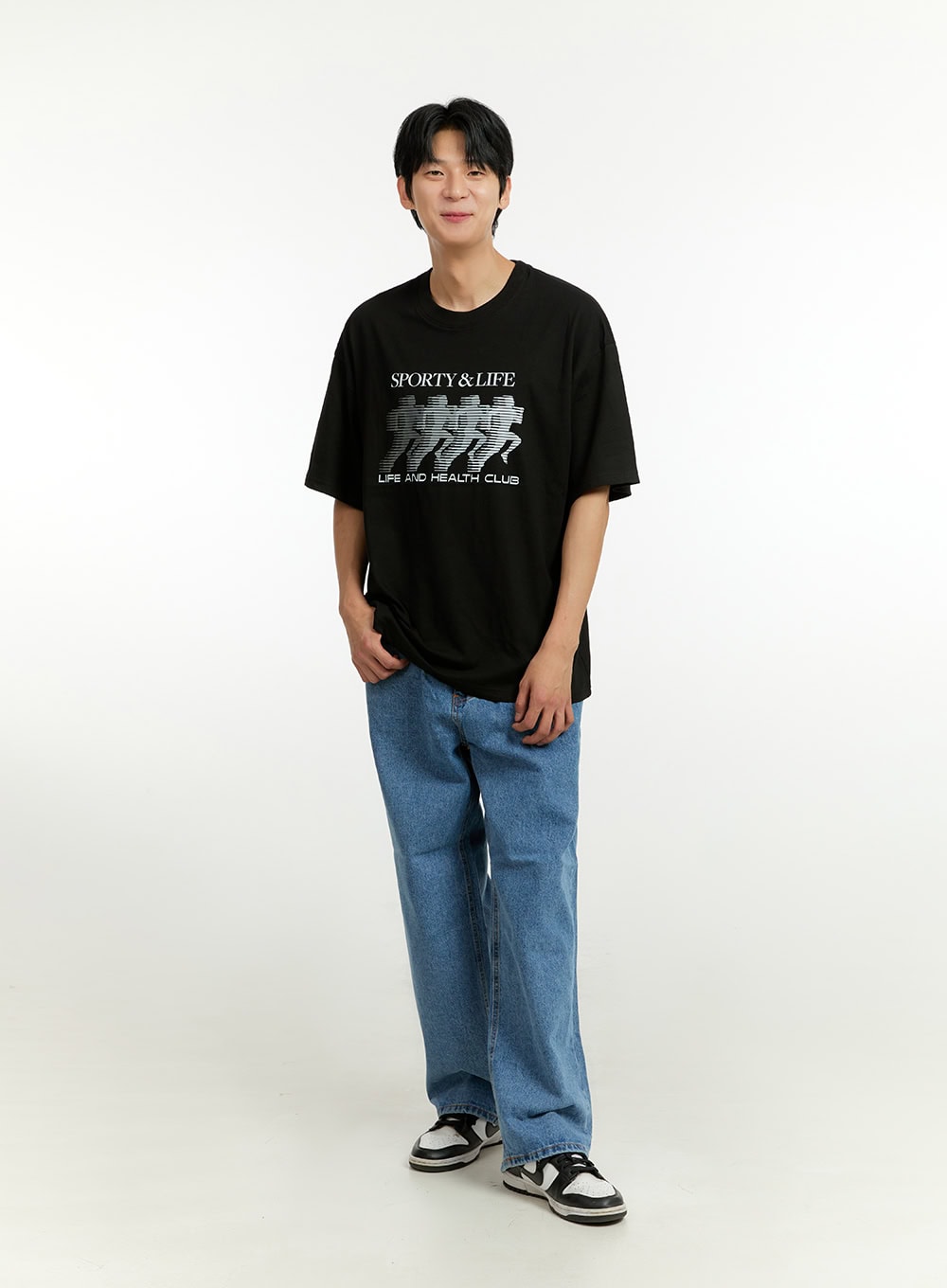 Men's Wide Fit Jeans IL412 in blue, full-length front shot on model facing forward, loose wide-leg silhouette, styled with black oversized tee and chunky sneakers.