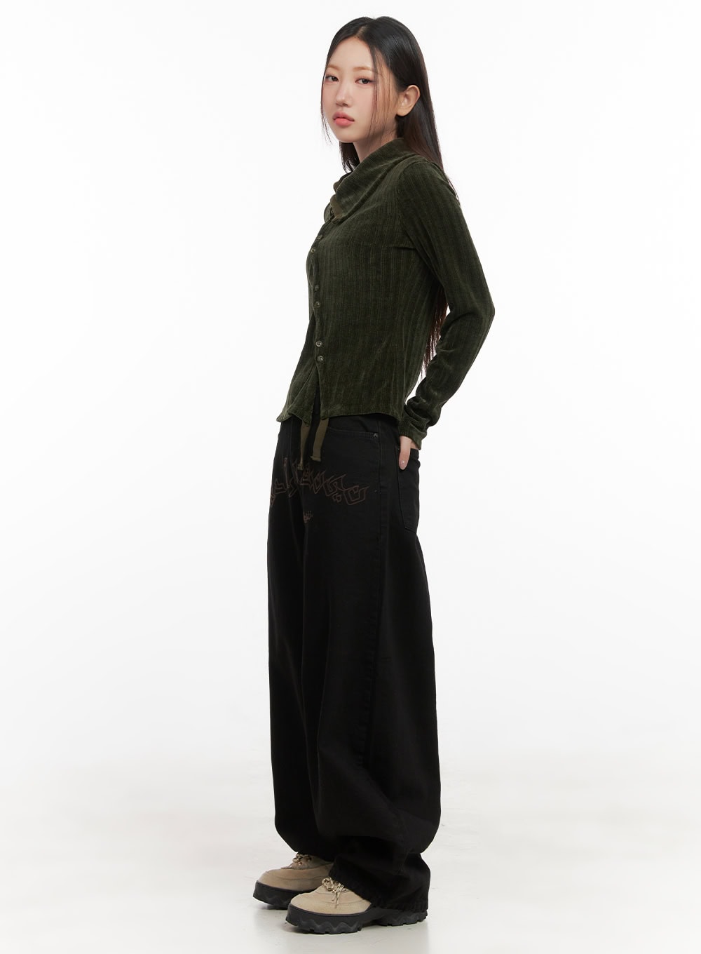 Yasmin Denim Wide Fit Jeans CD413 in black, side view on model, baggy wide-leg denim with lettering graphic at hip, paired with green hooded ribbed top and chunky sneakers.