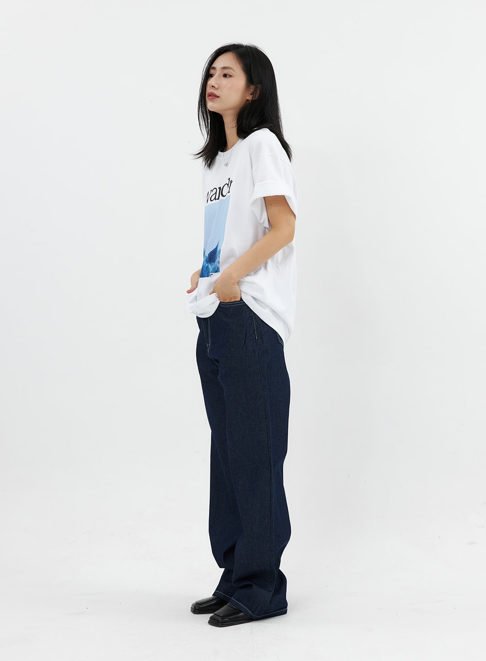 Stitched Jeans OO305 in Blue, side view on model, wide-fit indigo cotton denim with visible contrast stitch detail, hands in pockets, casual styling.