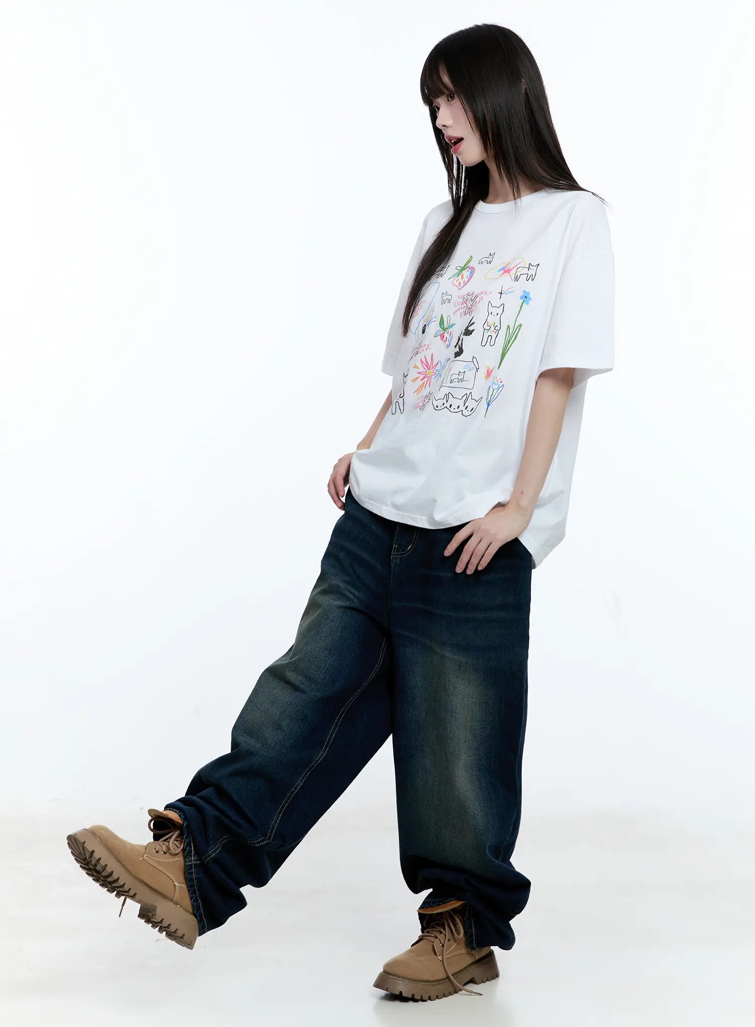 Jinnie Washed Wide-Leg Jeans CG511 in dark blue, three-quarter side view on model in motion, paired with white graphic tee and tan boots, wide-leg pooling at hem, washed cotton denim.
