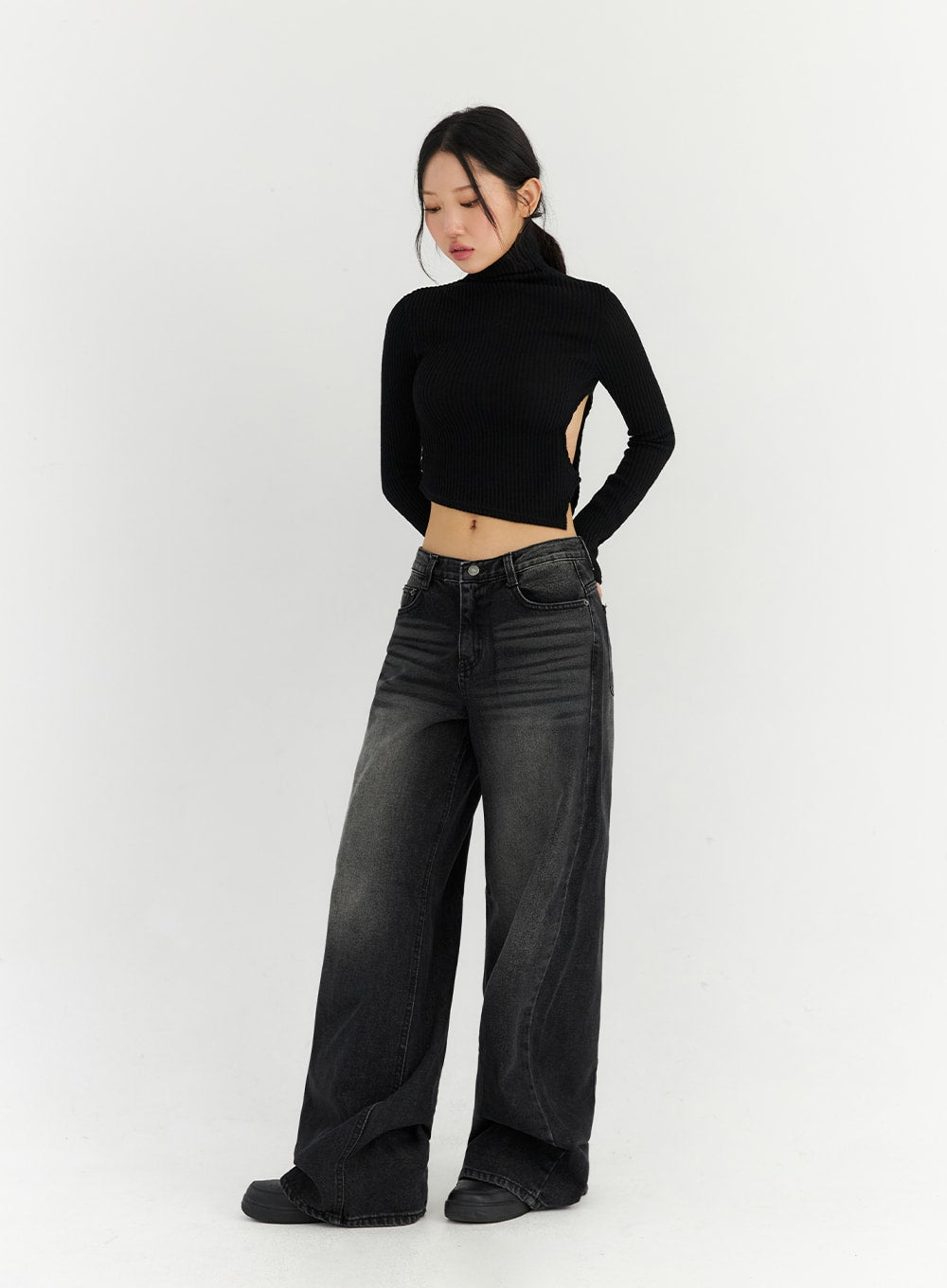 Back Slit Washed Wide Leg Jeans CN306 in Black, front three-quarter view on model looking down, washed black cotton denim with faded thigh detail, wide leg silhouette, low waist.