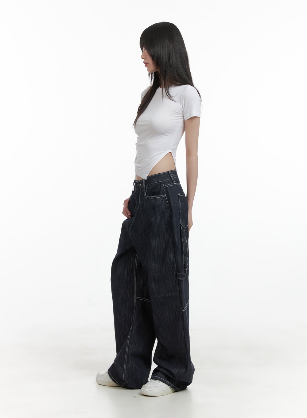 Low-Rise Strap Baggy Jeans CY414 in dark blue, side view on model showing low-rise waist and voluminous wide leg, paired with white crop tee and white sneakers.