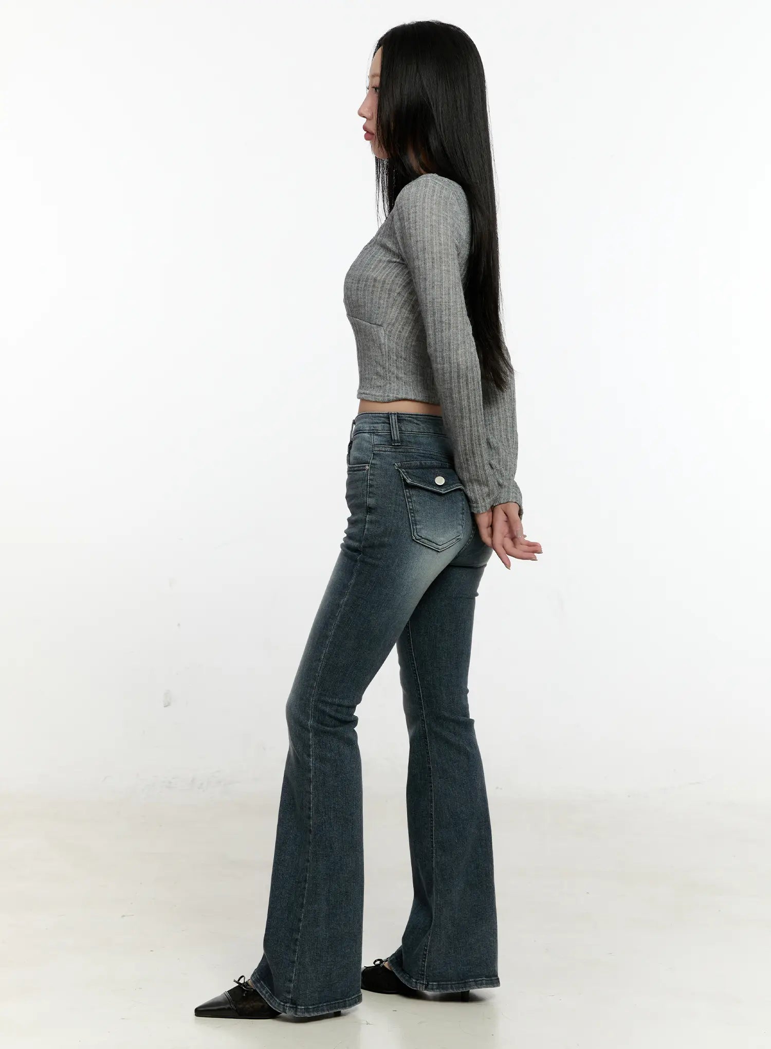 Marley Hip-Pad Denim Bootcut Jeans CN506 in dark blue, side view on model, hip-pad silhouette and flared bootcut hem visible, paired with grey ribbed crop top and black mules.