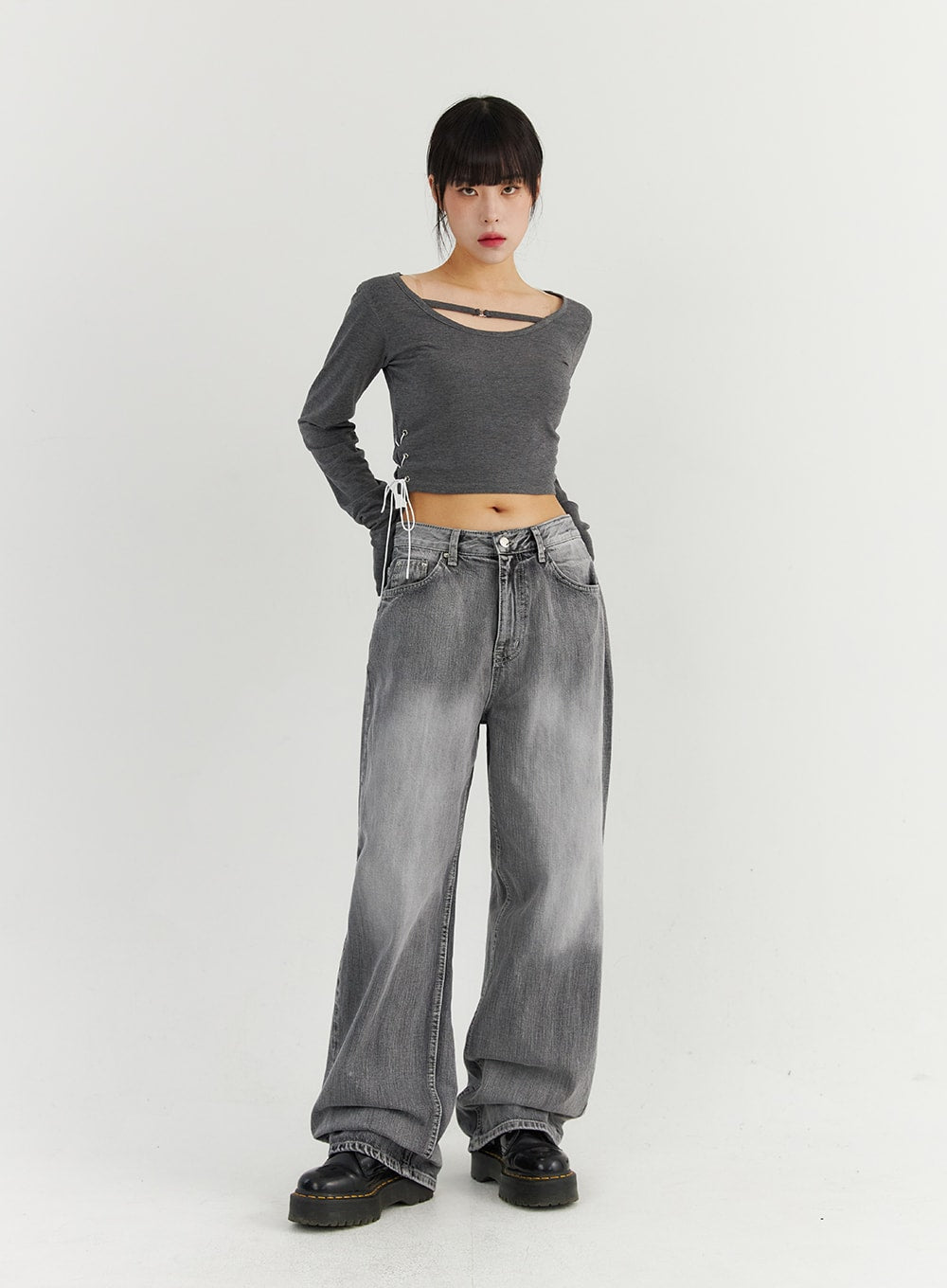Grey Washed Wide Leg Jeans CO323 in Gray, full-body front view on model with hand on hip, relaxed wide-fit cotton denim with washed gradient, paired with lace-up gray crop top and black boots.