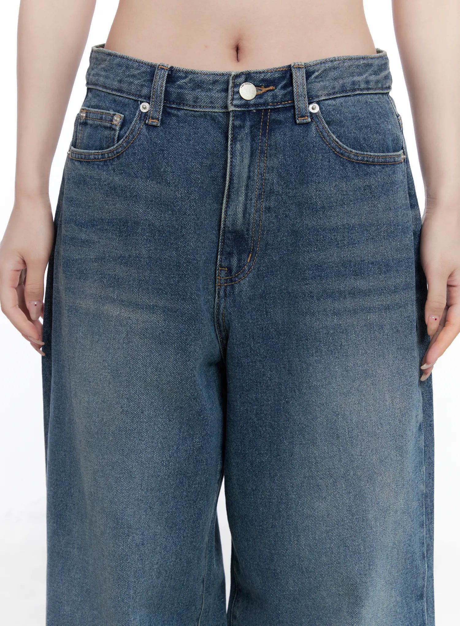 Amalia Wide Leg Vintage Washed Jeans CG529 in blue, close-up waist detail on model showing mid-rise waistband, silver button, front pockets, and vintage-washed cotton denim texture.