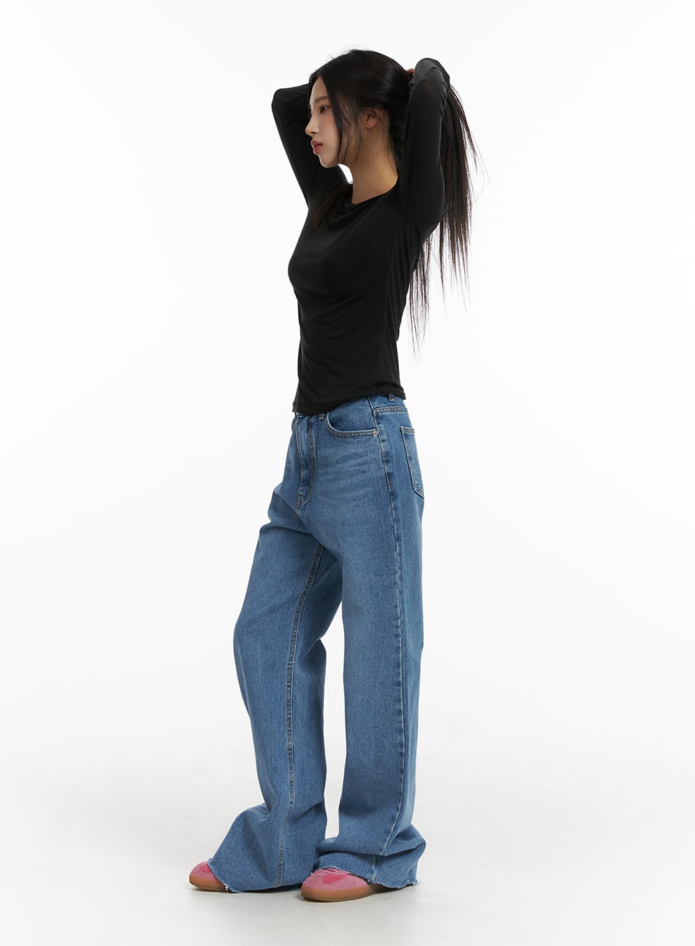 Blue Denim Bootcut Jeans CJ431 in blue, full-length side shot on model with arms raised, showing bootcut silhouette and raw frayed hem, washed cotton denim, paired with black long sleeve top.