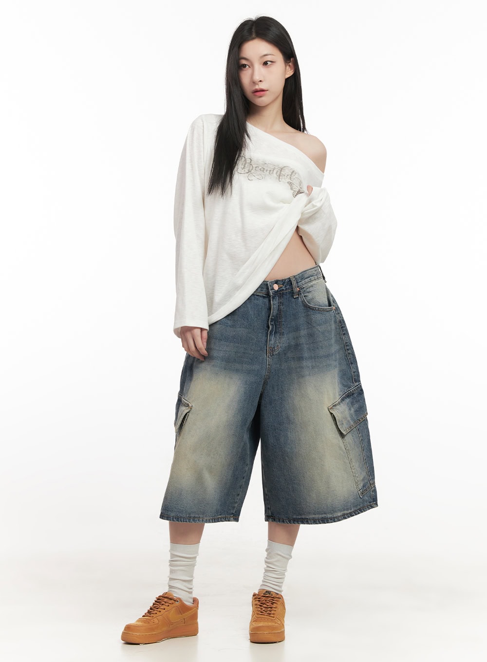 Cargo Bermuda Denim Shorts CF514 in dark blue, front full-body shot on model, wide-fit midi washed denim with cargo pockets, paired with white off-shoulder graphic long-sleeve top and tan sneakers.
