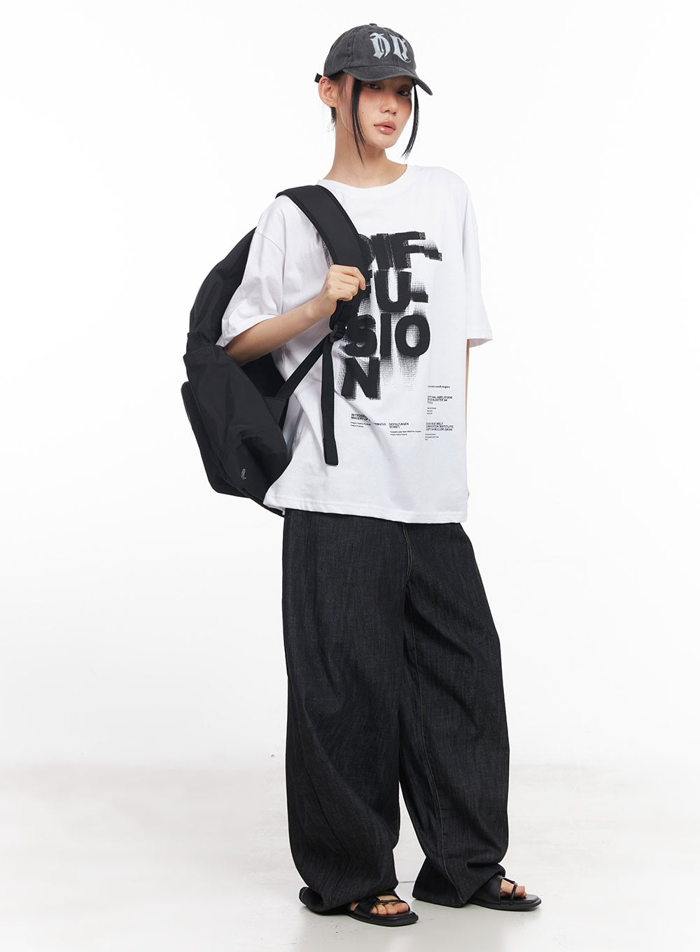 Elvie Baggy Jeans CY528 in black, full-length street-style shot on model, voluminous wide-leg denim paired with graphic tee, cap, and backpack.