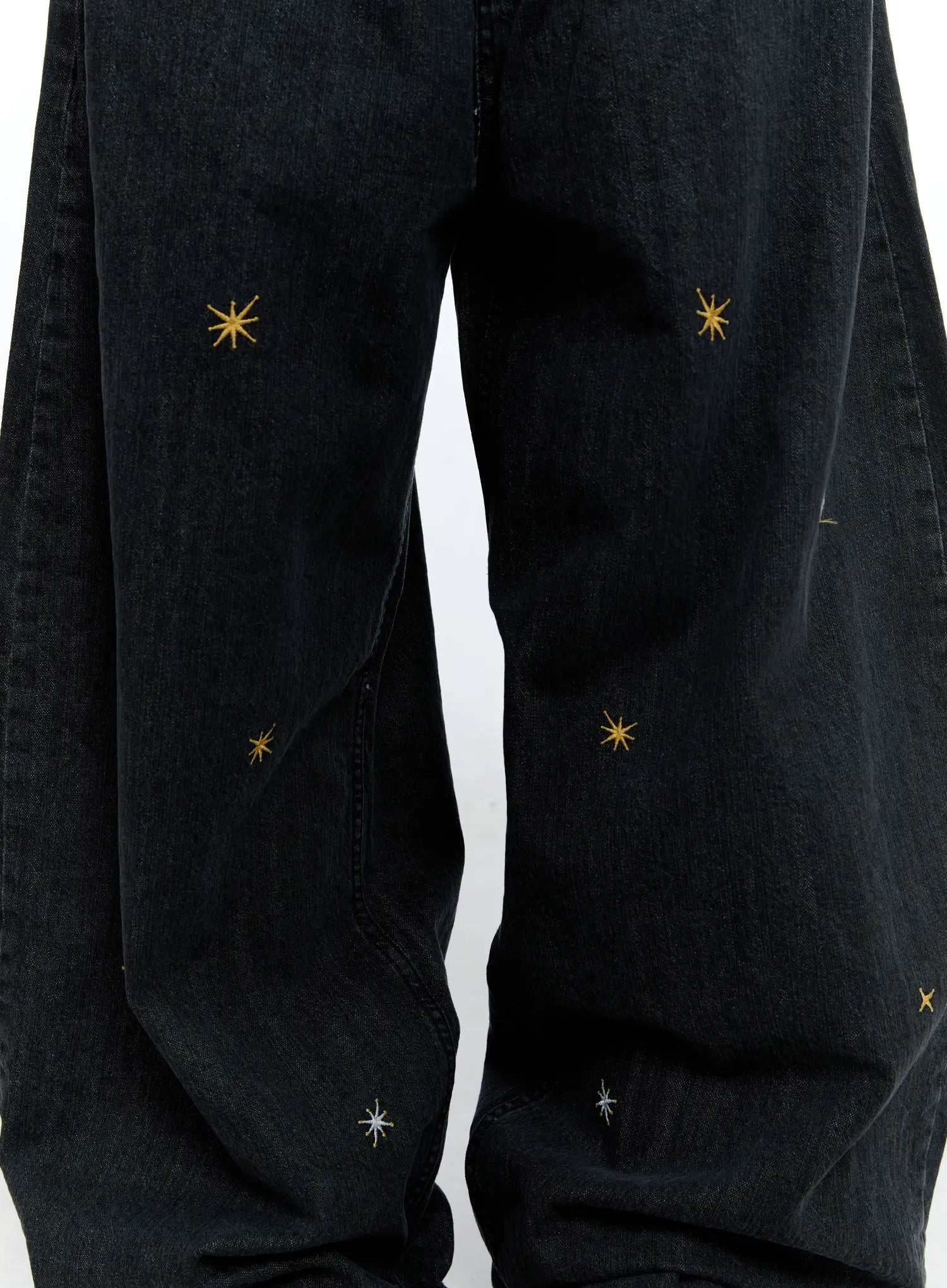Wynter Star Embroidered Denim Jeans CG507 in black, close-up detail of leg panels, scattered gold and silver 8-point star embroidery on washed cotton denim, wide-leg drape visible.