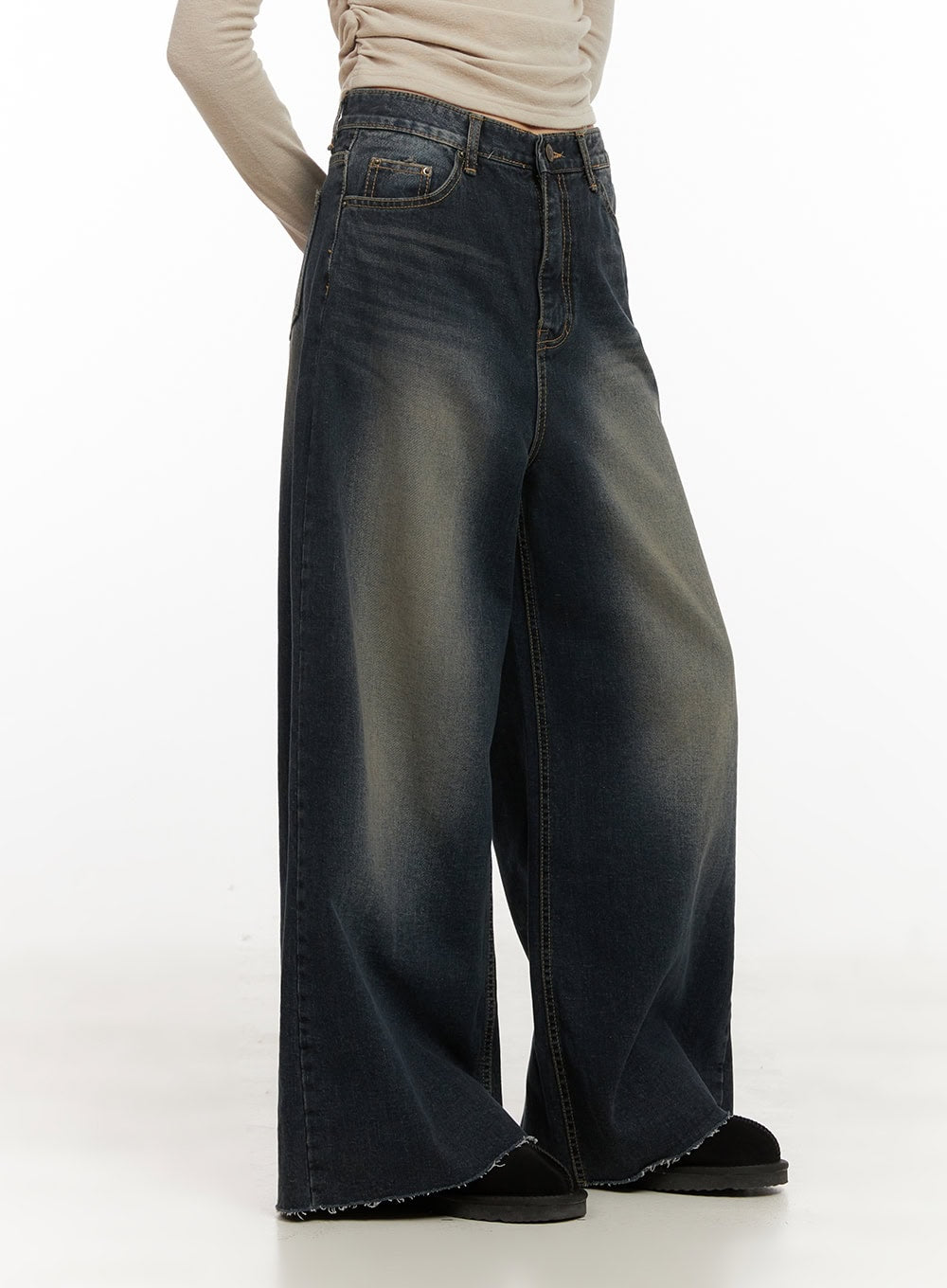 Tasha Low Waist Washed Wide Leg Jeans CD410 in dark blue, side angle on model, low-waist washed denim with yellow-tinted fading, sweeping wide leg, raw frayed hem, styled with beige top.