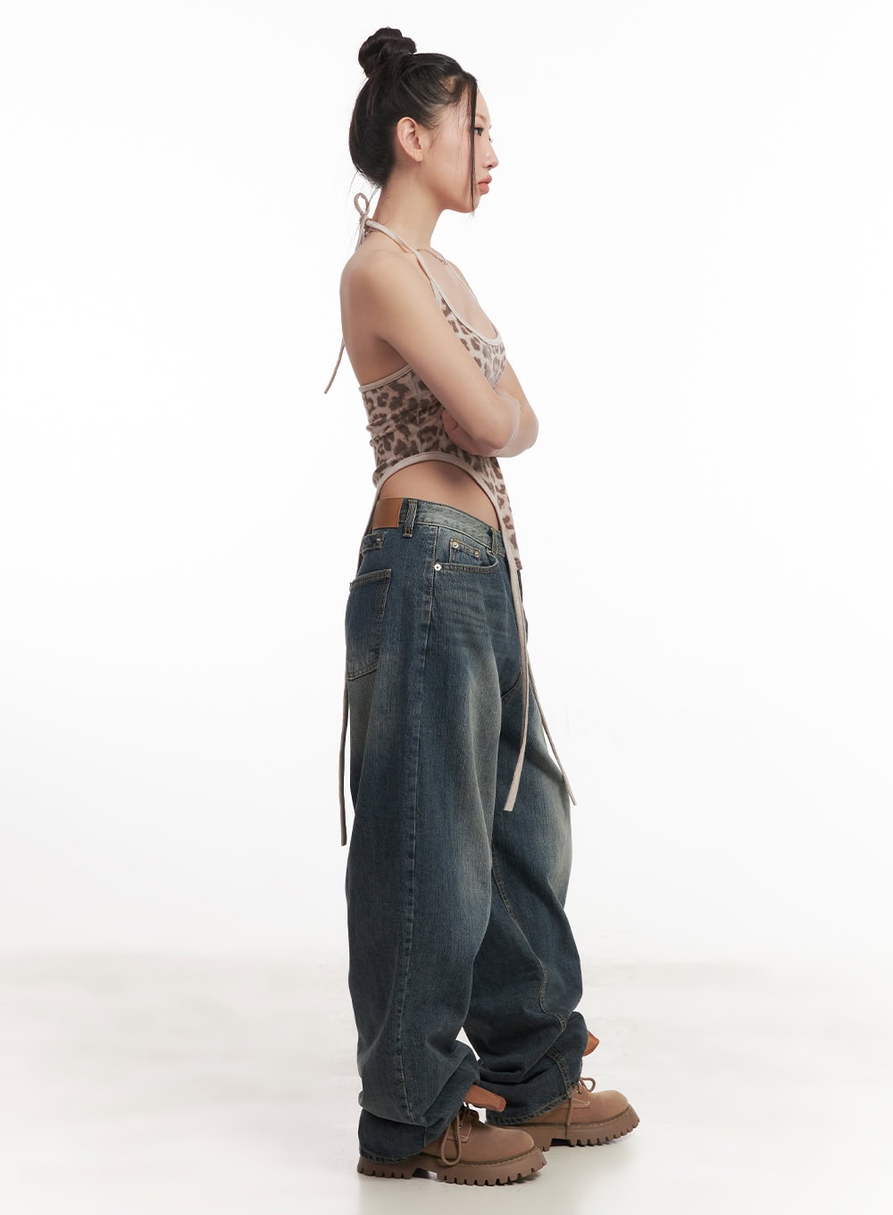 Leilani Washed Baggy Jeans CM531 in dark blue, side view on model with arms crossed, wide-fit washed denim showing volume and length, paired with leopard halter top.
