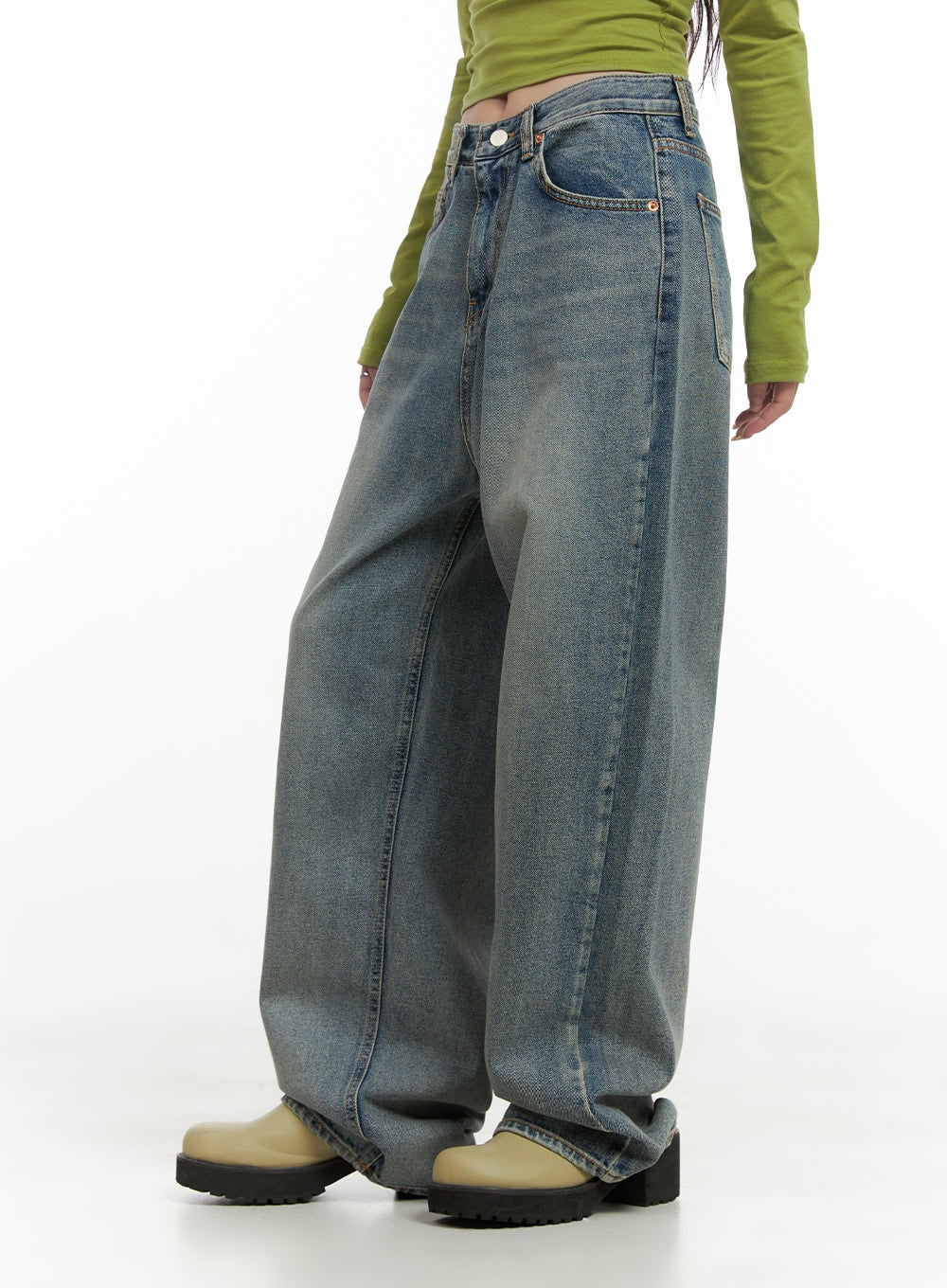 Millie Washed Baggy Jeans CG421 in Blue, side view on model, wide-fit washed denim showing seam line and roomy leg silhouette, paired with green crop top and chunky boots.