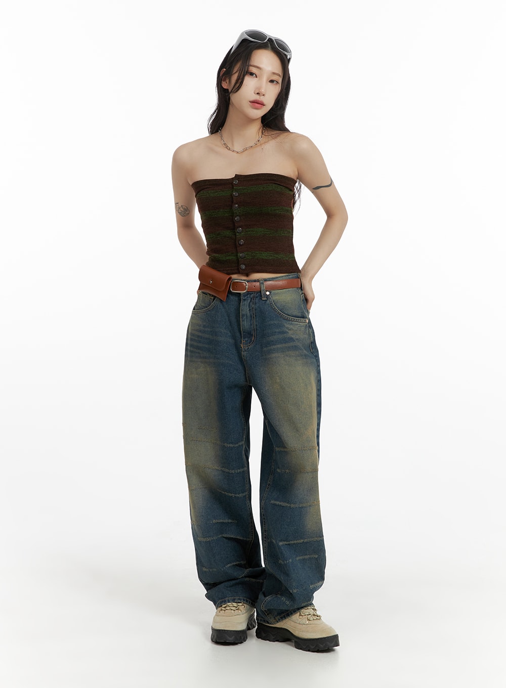 Scratch Textured Baggy Jeans CM405 in washed indigo blue, full-body front shot on model, wide baggy silhouette with scratch stitch detailing, paired with striped bandeau top, brown belt bag, and chunky sneakers.