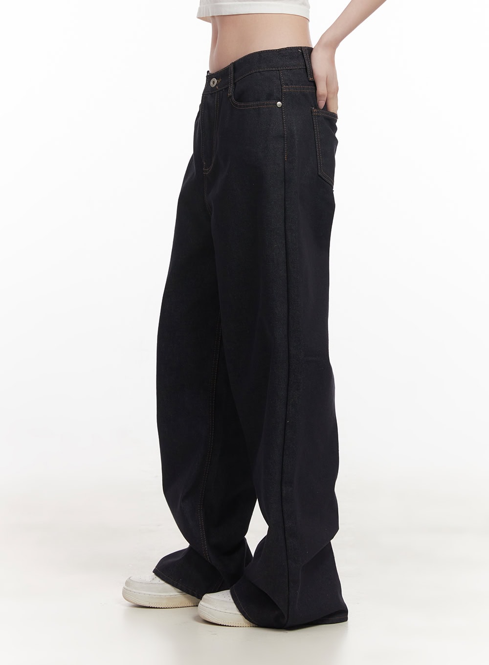 Jasmin Wide-Leg Jeans CF514 in dark blue, side view on model, wide-leg baggy cotton denim showing roomy silhouette, low rise, hand tucked in waistband, white sneakers.