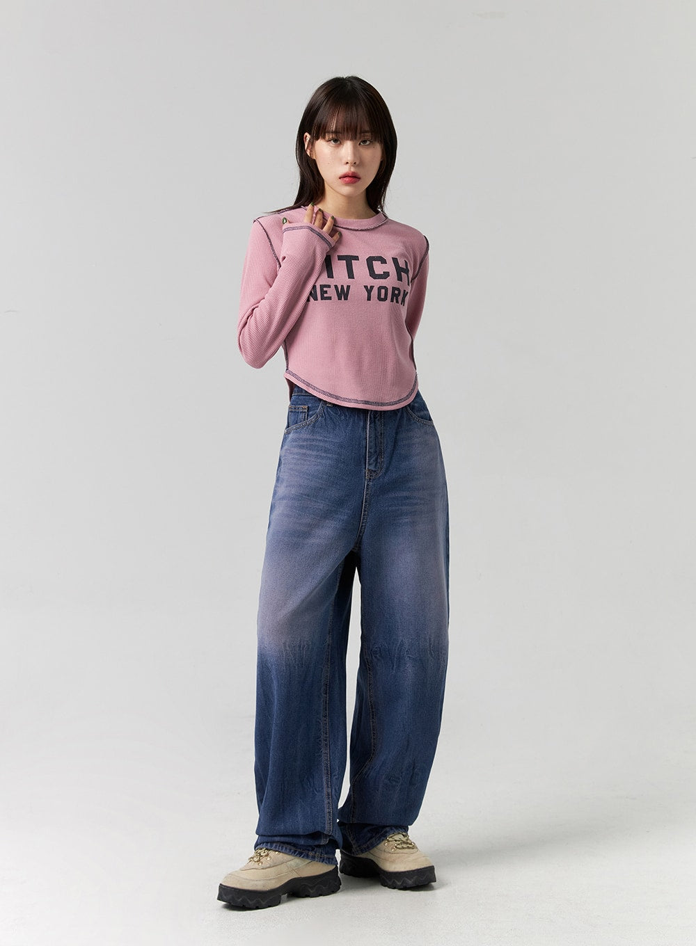 Wide Leg Cotton Jeans CG331 in blue, three-quarter front view on model with hand raised, washed cotton denim wide leg, styled with pink crop tee and sneakers.