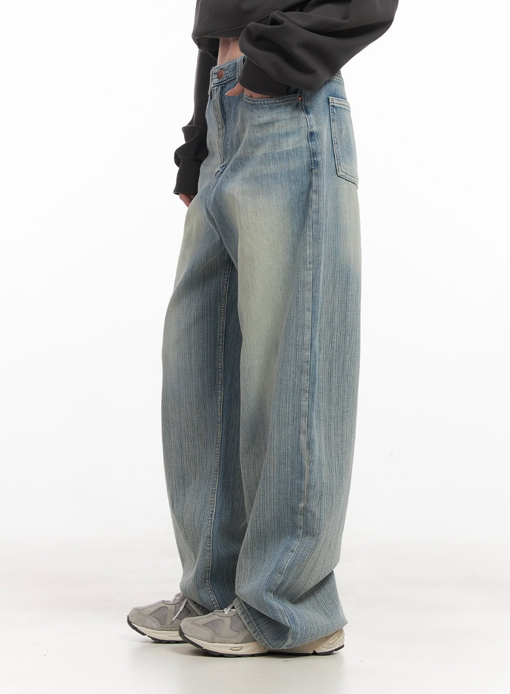 Nicola Washed Wide-Leg Jeans CF514 in light blue, side view on model, showing wide-leg volume and vertical wash texture, paired with dark grey sweatshirt and chunky sneakers.