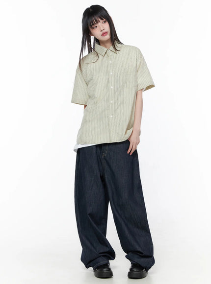 Oversized Short Sleeve Button-Up Shirt CU519 in light beige, full-body front view on model, striped cotton fabric, boxy oversized silhouette with chest pocket, layered over white tee with wide-leg dark denim.