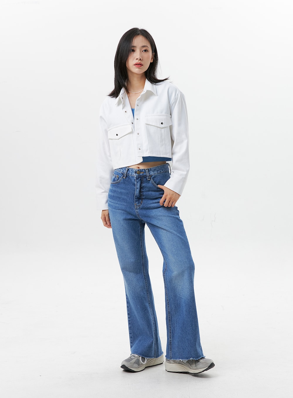 Straight-Leg Jeans OG318 in medium blue, three-quarter front angle on model, high-rise straight-leg denim with flared hem, styled with white cropped jacket and blue crop top.