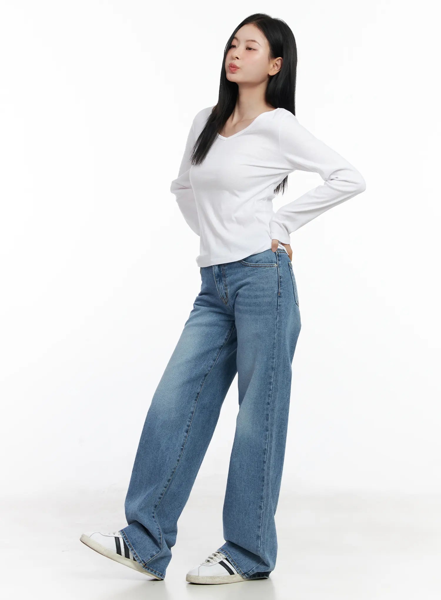 Maisy Casual Wide Leg Jeans CJ519 in blue, three-quarter side view on model with hand on hip, washed wide-leg silhouette, paired with white long-sleeve top and sneakers.