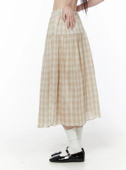 Plaid Flare Maxi Skirt CU519 in beige, side view on model with hand on waist, showing tiered flare shape and elastic waistband, semi-sheer lightweight plaid, styled with white socks and black Mary Janes.