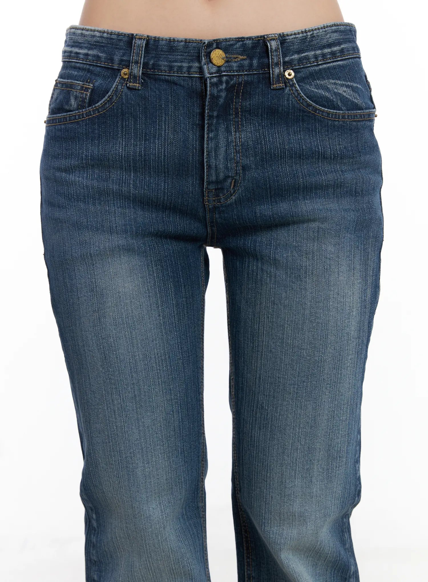 Astrid Low Rise Flared Bootcut Jeans CJ514 in blue, close-up front detail on model, low-rise waistband, gold button and rivet, front pockets with contrast stitching, washed denim texture.